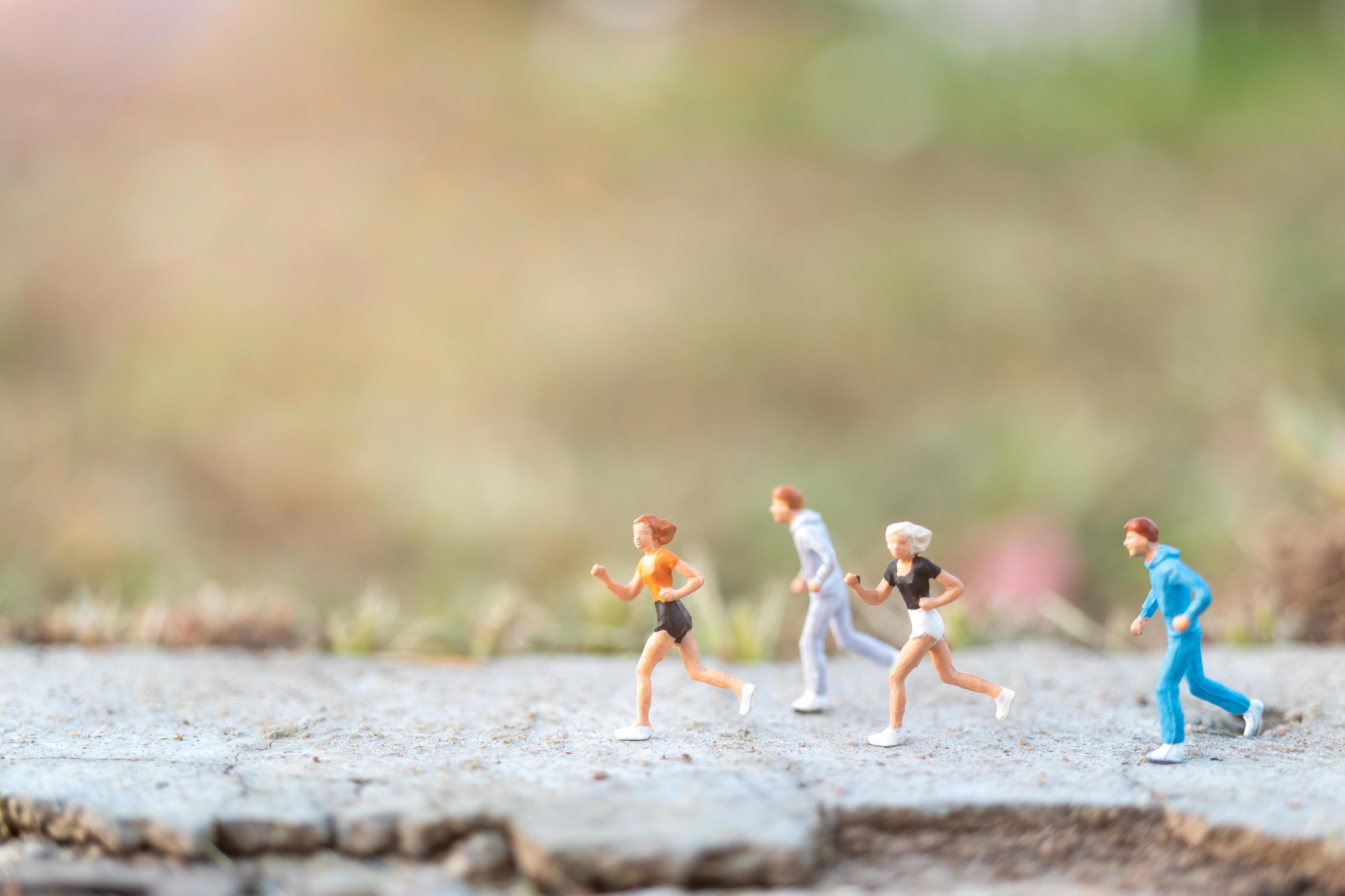 Miniature people running on a road with a nature background, health and lifestyle concept Stock Free