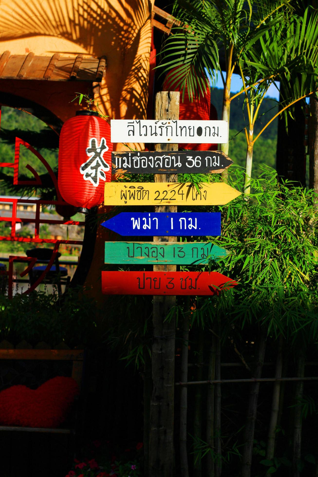 Thai Language on colorful Wooden signs for directions to various places in Thailand Stock Free