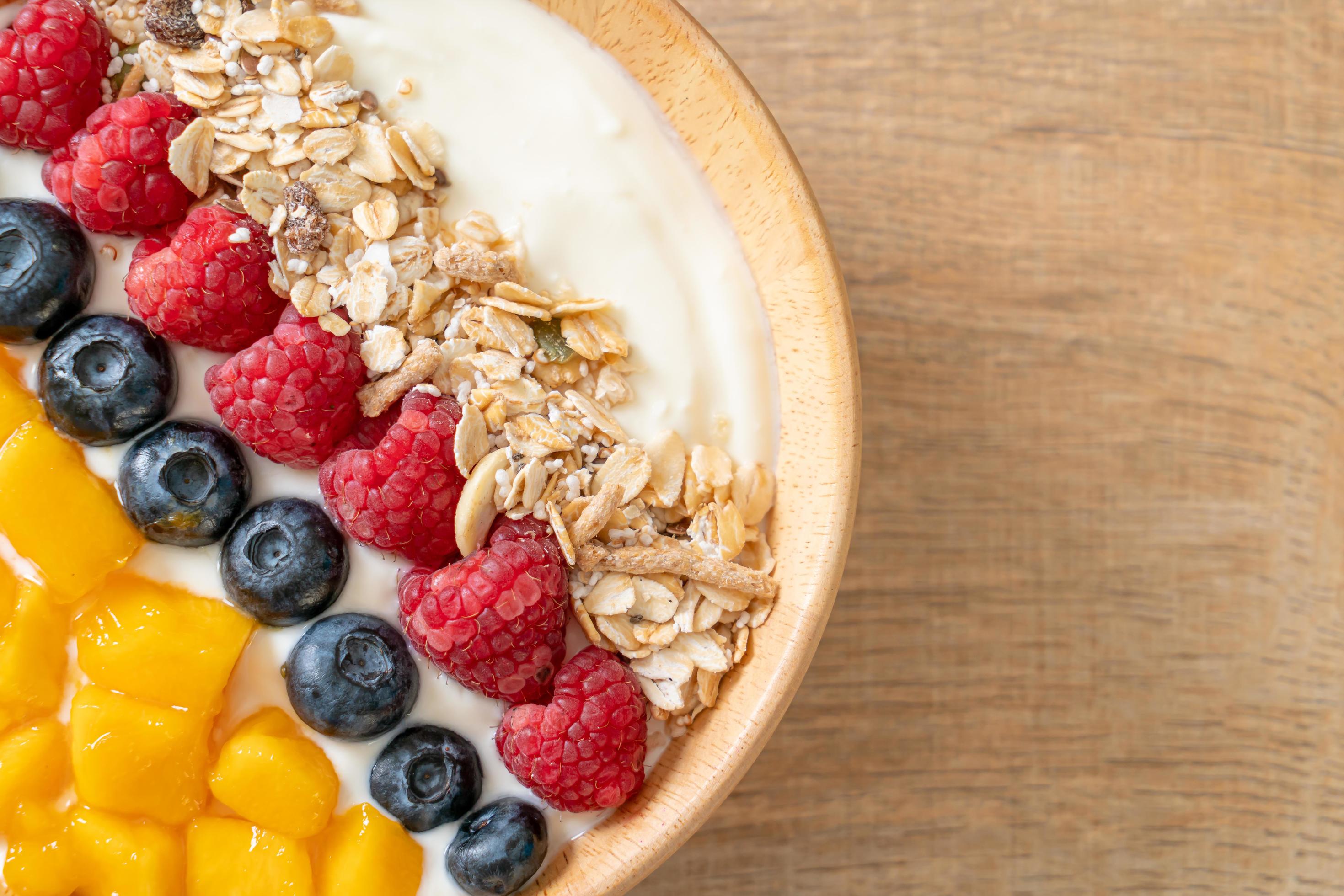 Homemade yogurt bowl with raspberry, blueberry, mango, and granola – healthy food style Stock Free