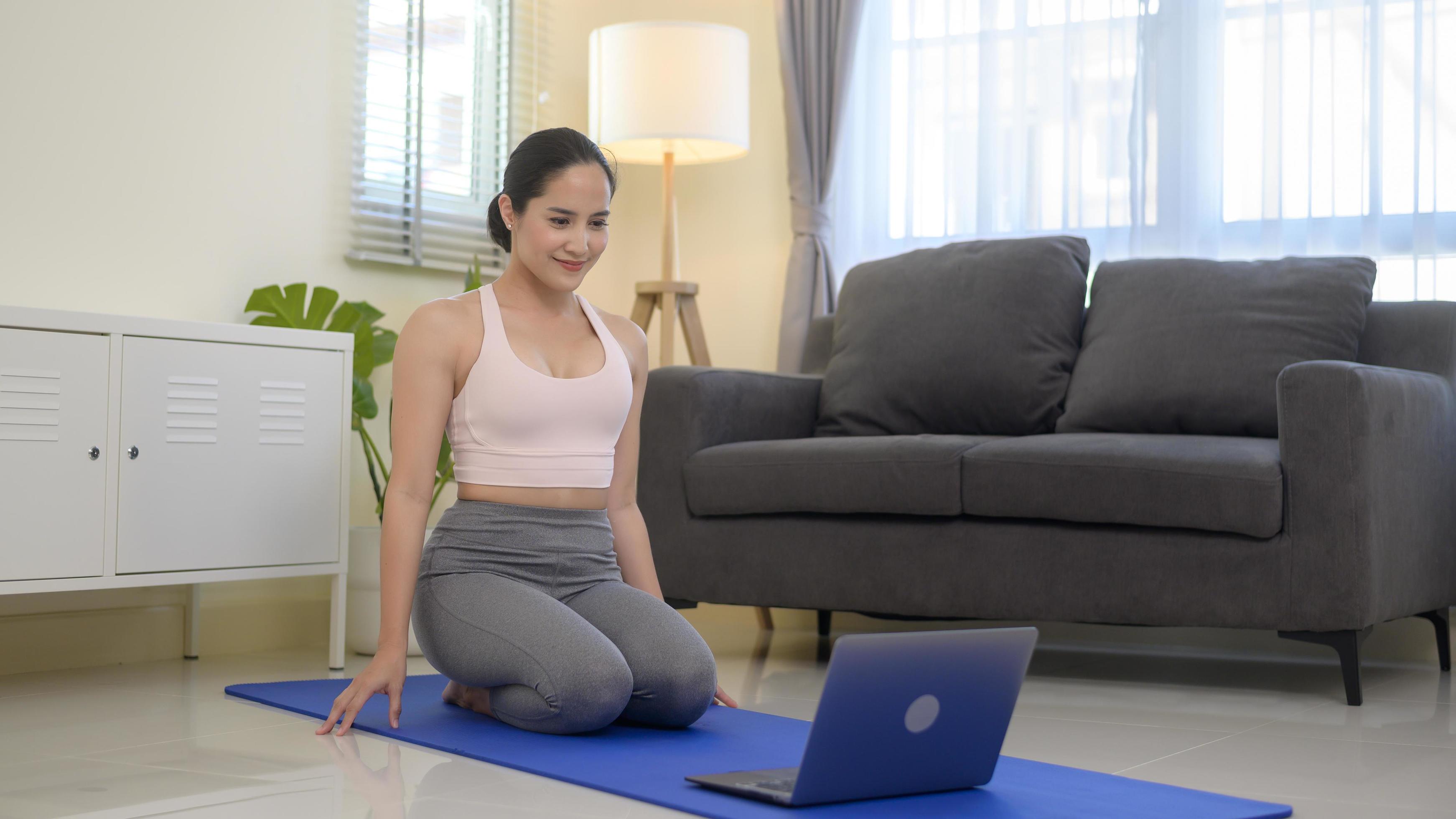 Fit young woman practicing yoga at home via online class with professional instructor, sport and healthy lifestyle concept. Stock Free