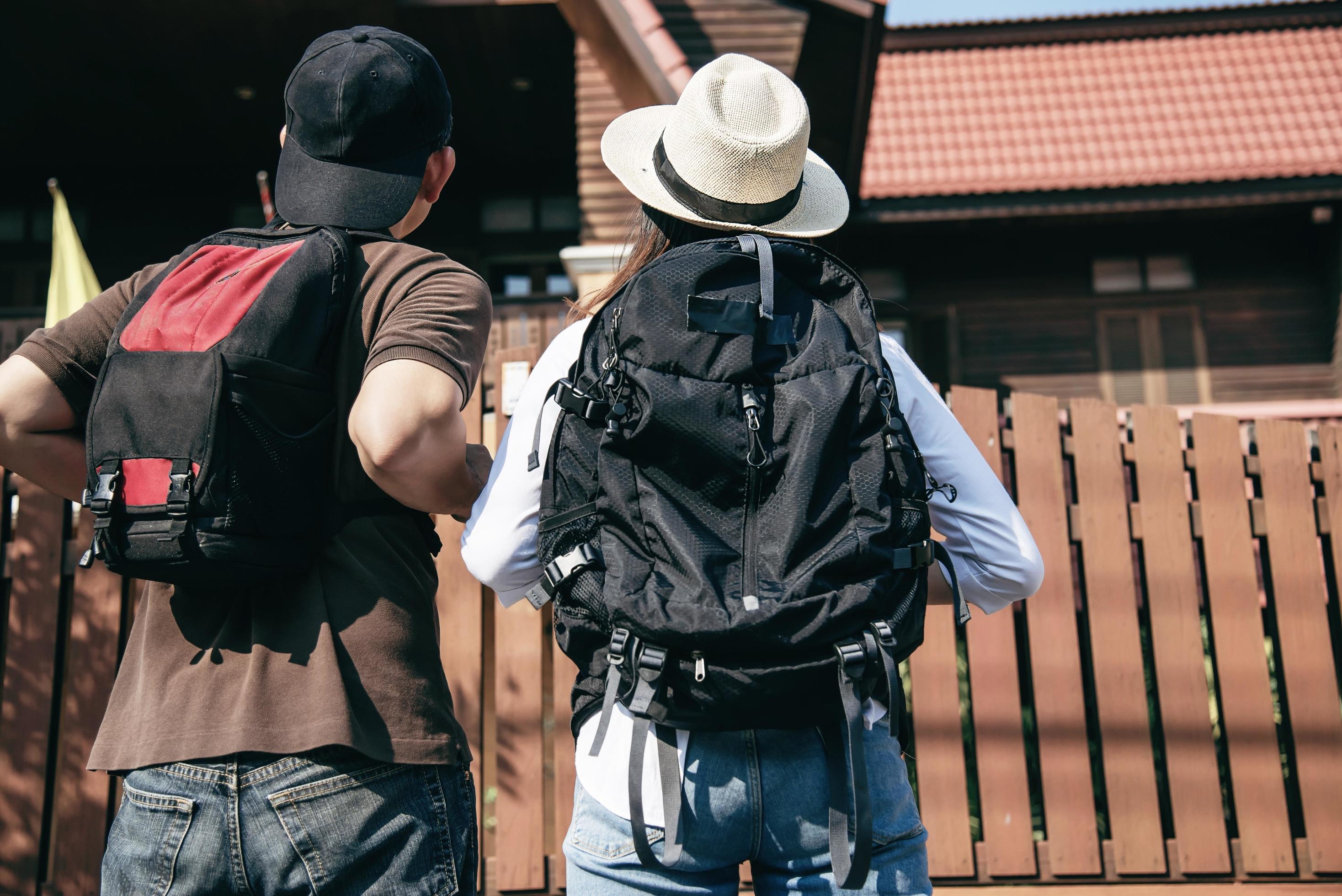 Asian backpack couple tourist holding city map crossing the road – travel people vacation lifestyle concept Stock Free