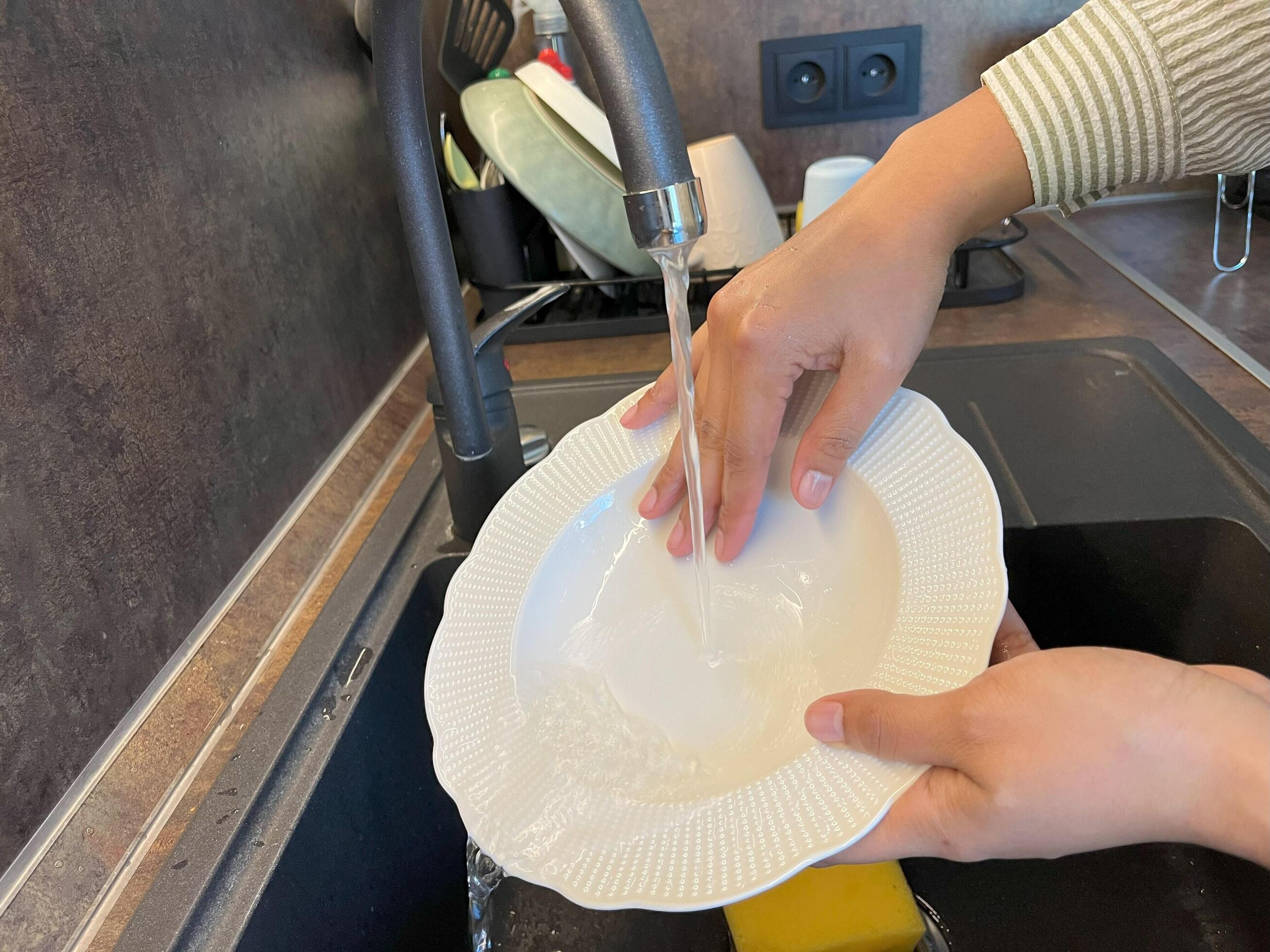 Close up of woman housewife is doing the dishes at home kitchen by using wash sponge and dishwashing soap. Clean the plate Stock Free