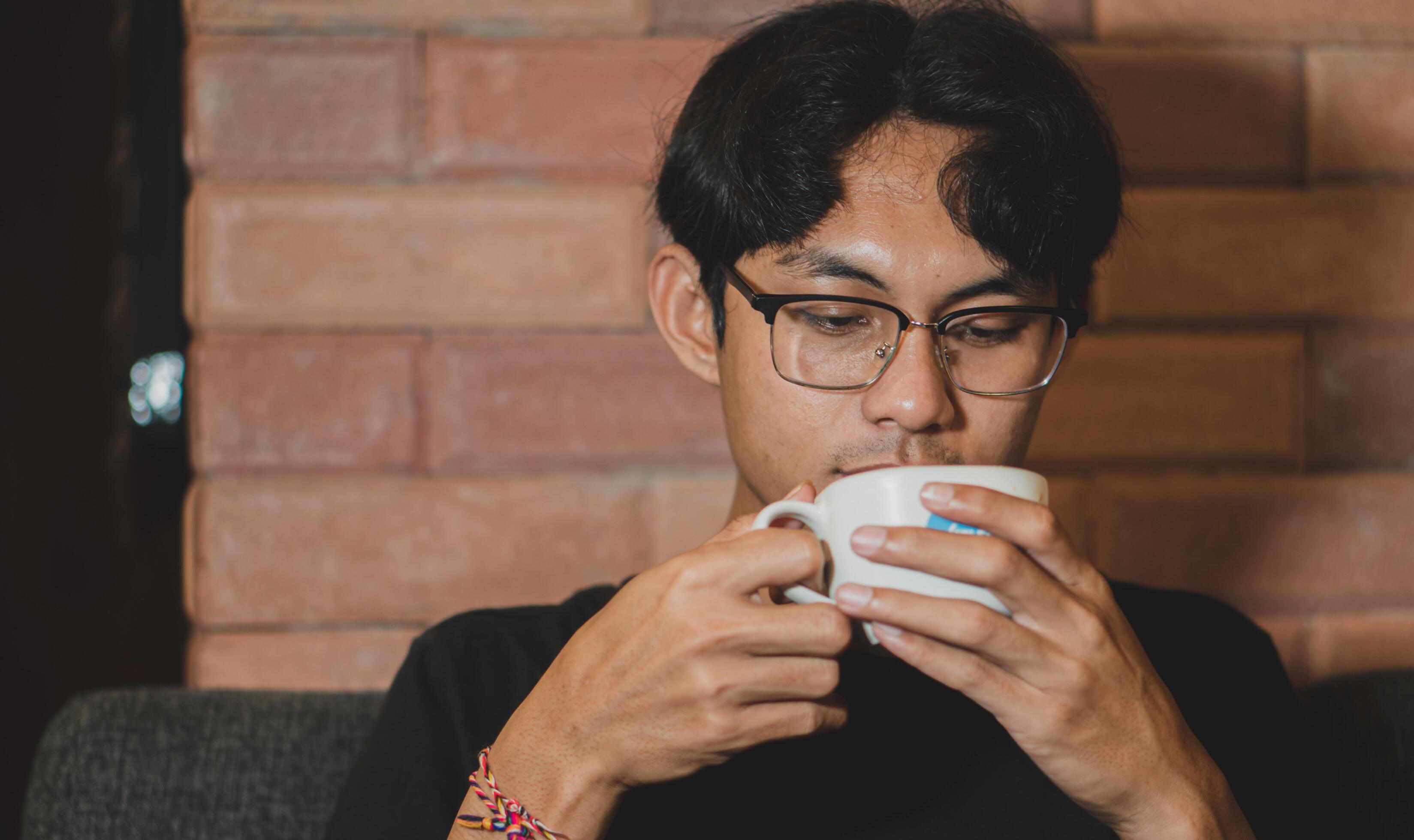 Man holds cup with coffee and enjoys. Business man drinking a coffee at the cafe. Stock Free