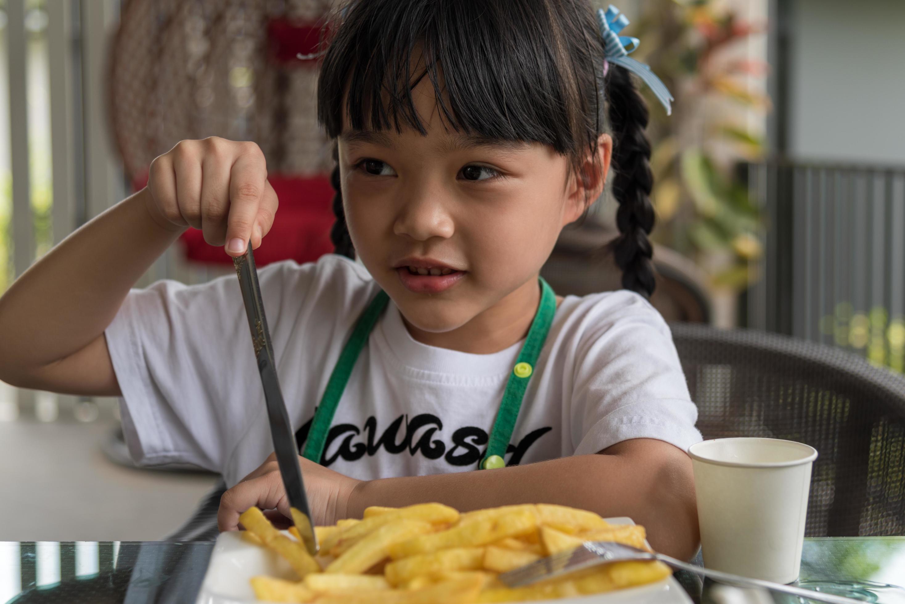 Young Asian girl eating french fries young kid fun happy potato fast food. Stock Free