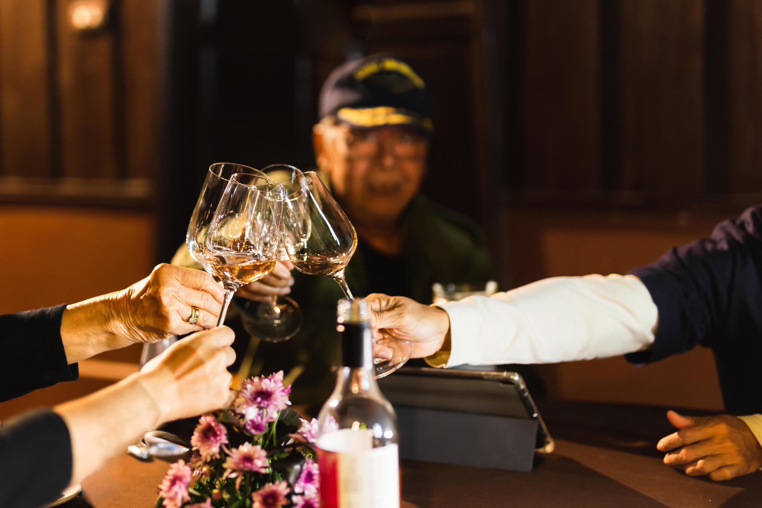 Happy family holding wine glasses toasting at dinner table. Stock Free