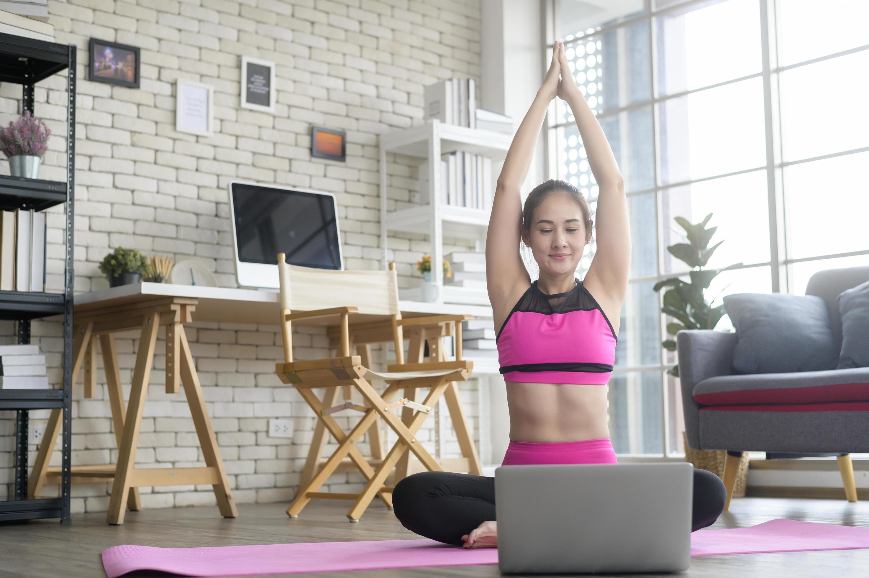 Fit young woman practicing yoga at home via online class with professional instructor, sport and healthy lifestyle concept. Stock Free