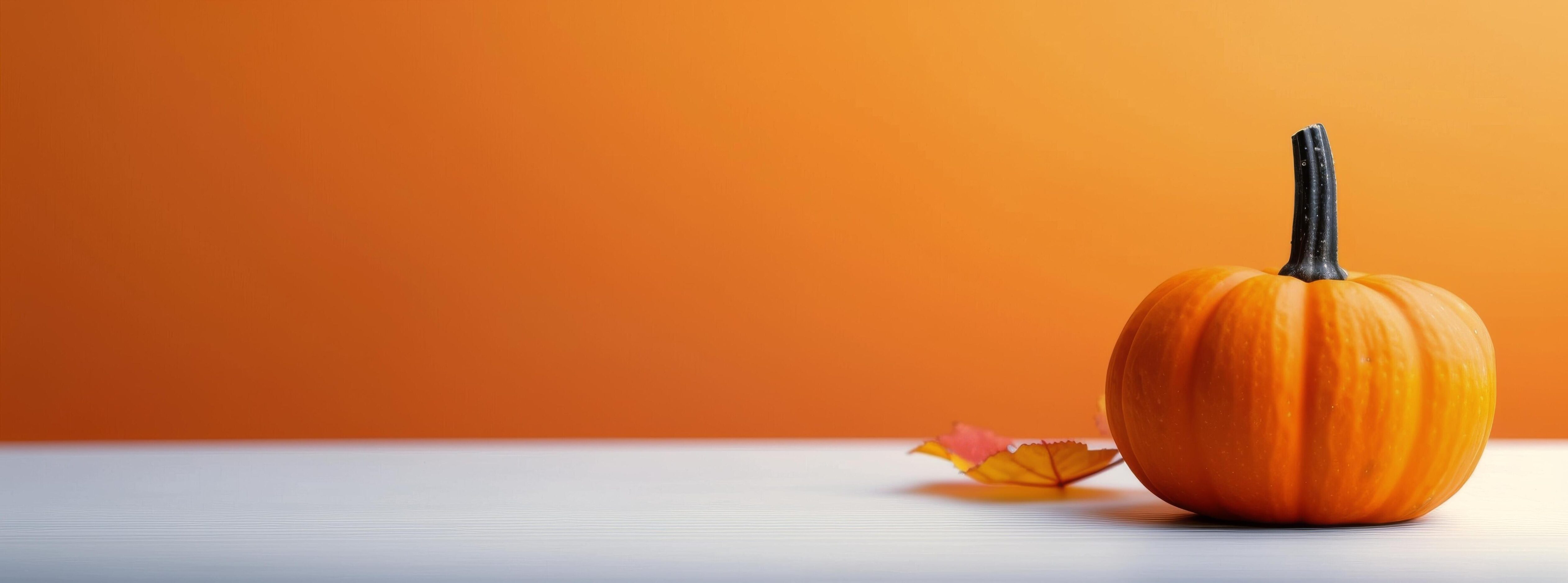 Vibrant Orange Pumpkin on White Surface Against Bright Orange Background in Autumn Stock Free