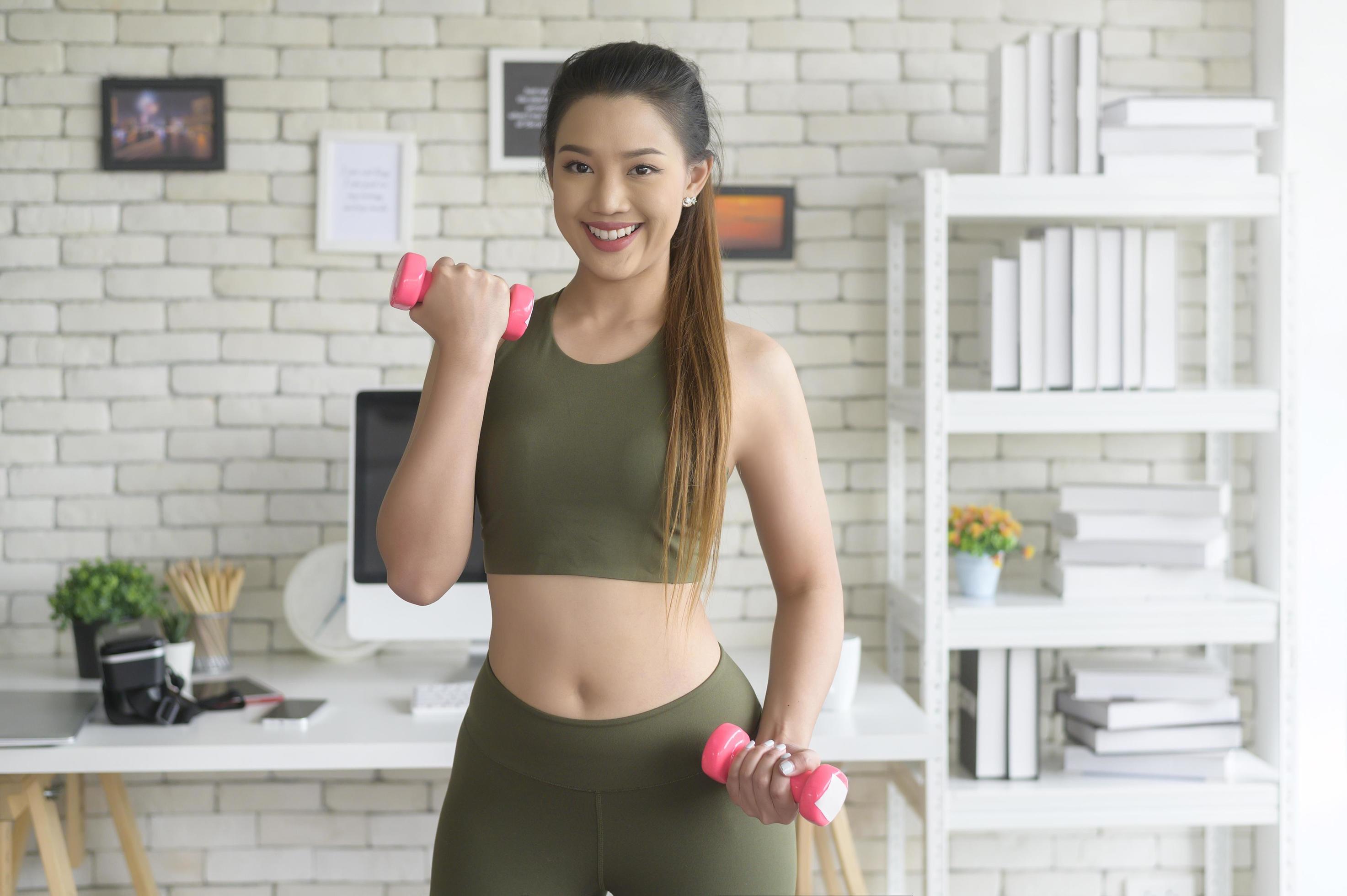 Young fitness woman in sportswear lifting dumbbells at home, Healthy and Lifestyles. Stock Free