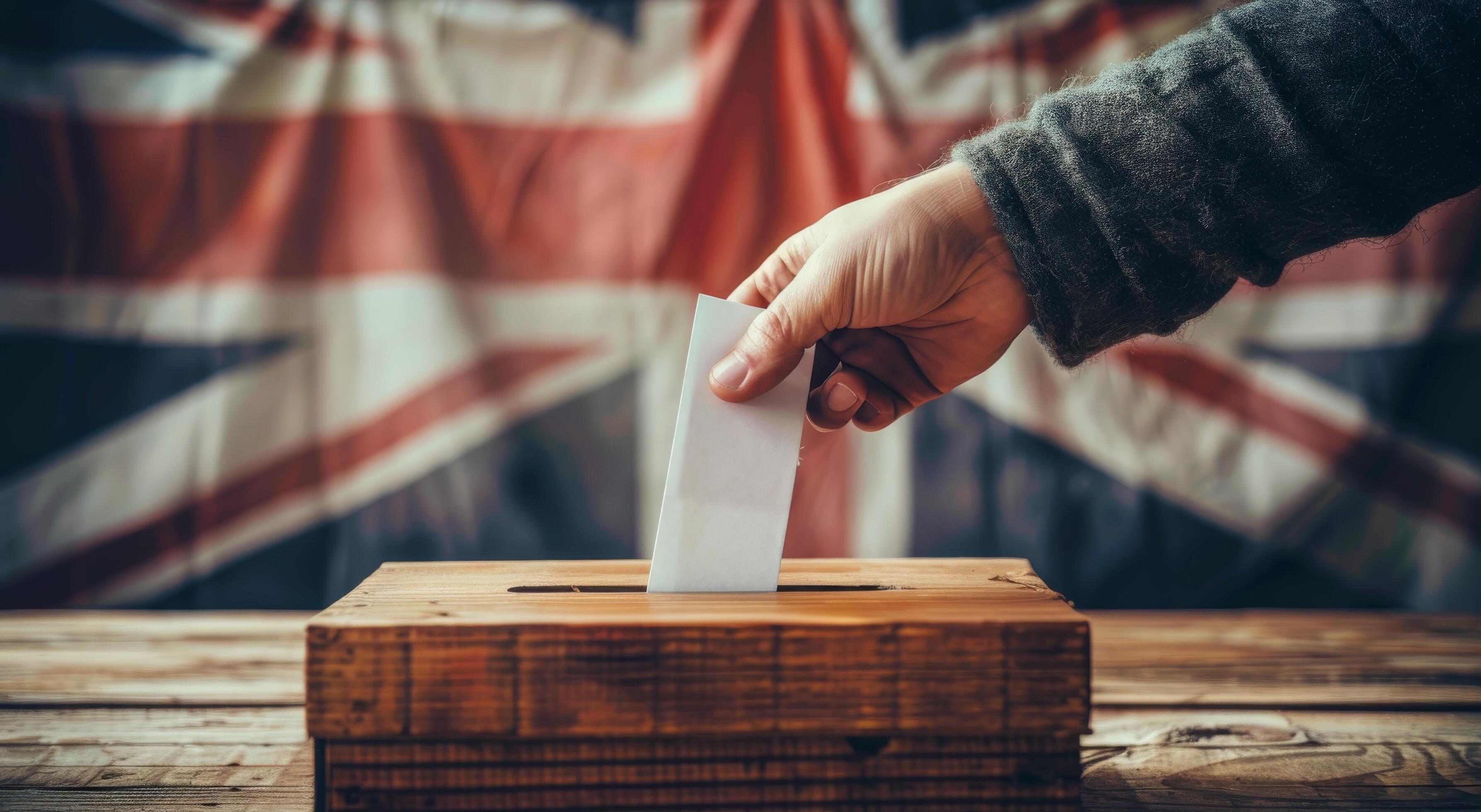 Hand Placing Ballot in Wooden Box With UK Flag Background Stock Free