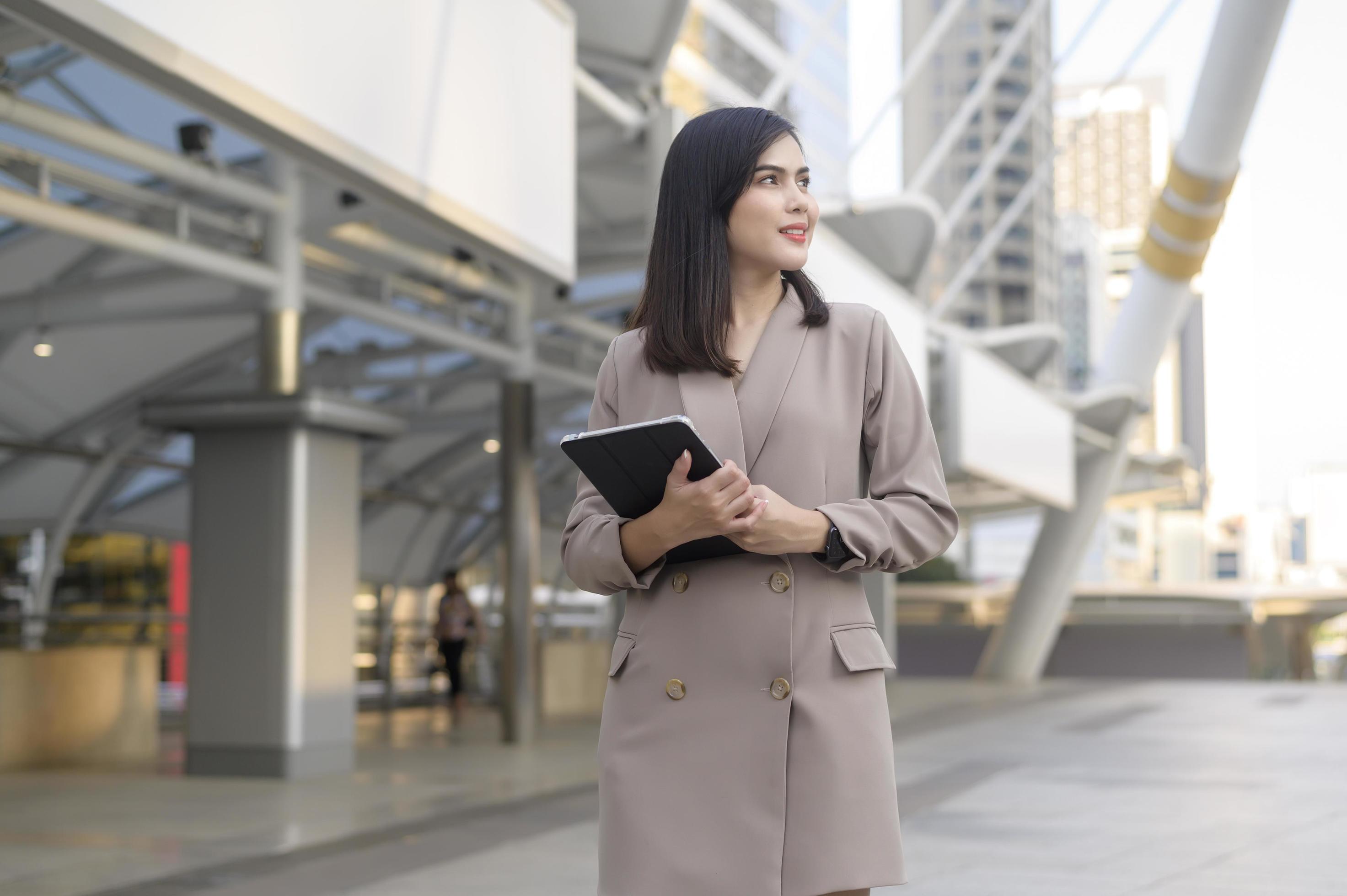 A young beautiful businesswoman is using tablet in Modern city , business technology , city lifestyle concept Stock Free