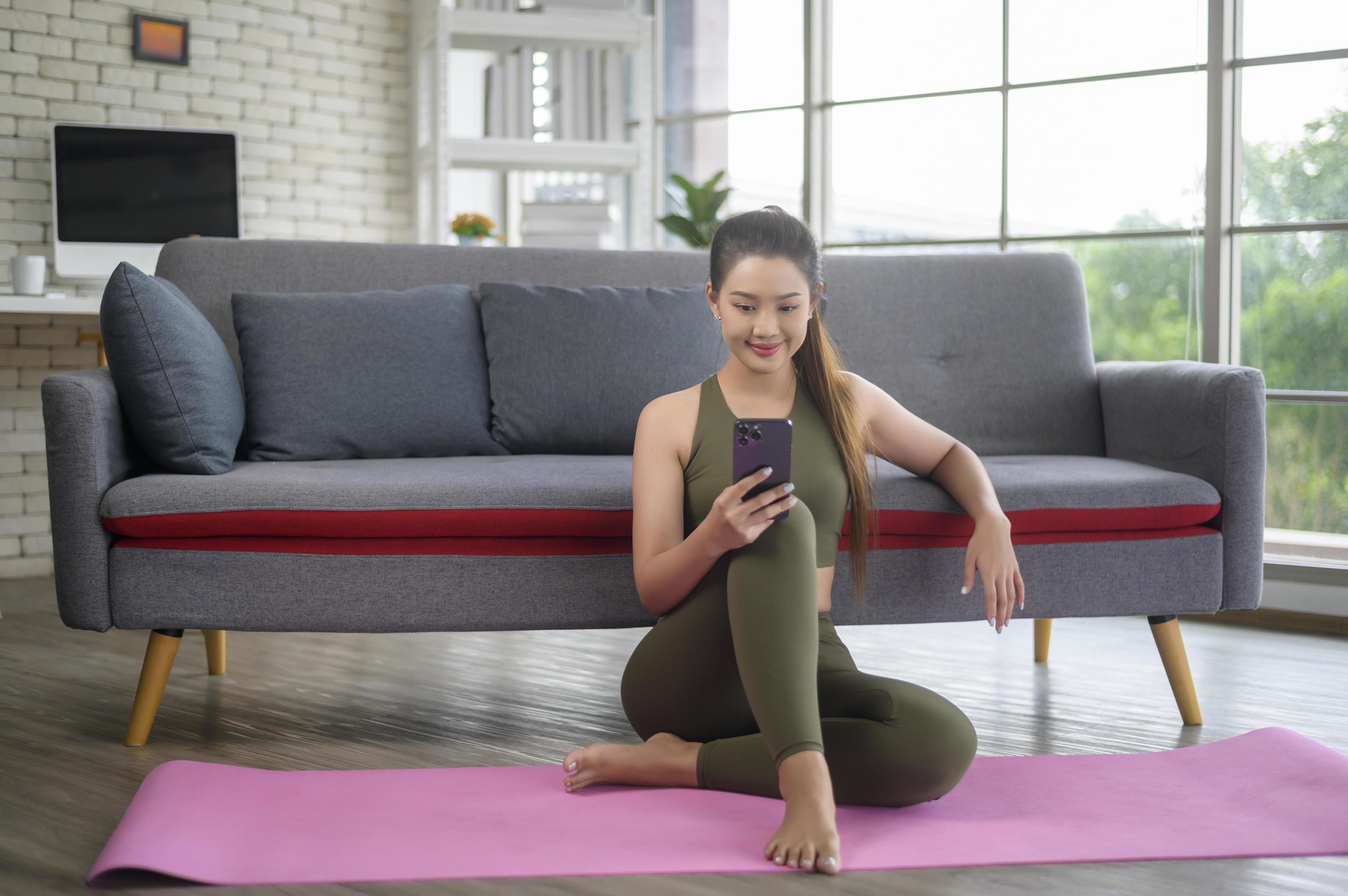 Young fitness woman in sportswear using smart phone while exercising at home, Healthy and Lifestyles. Stock Free