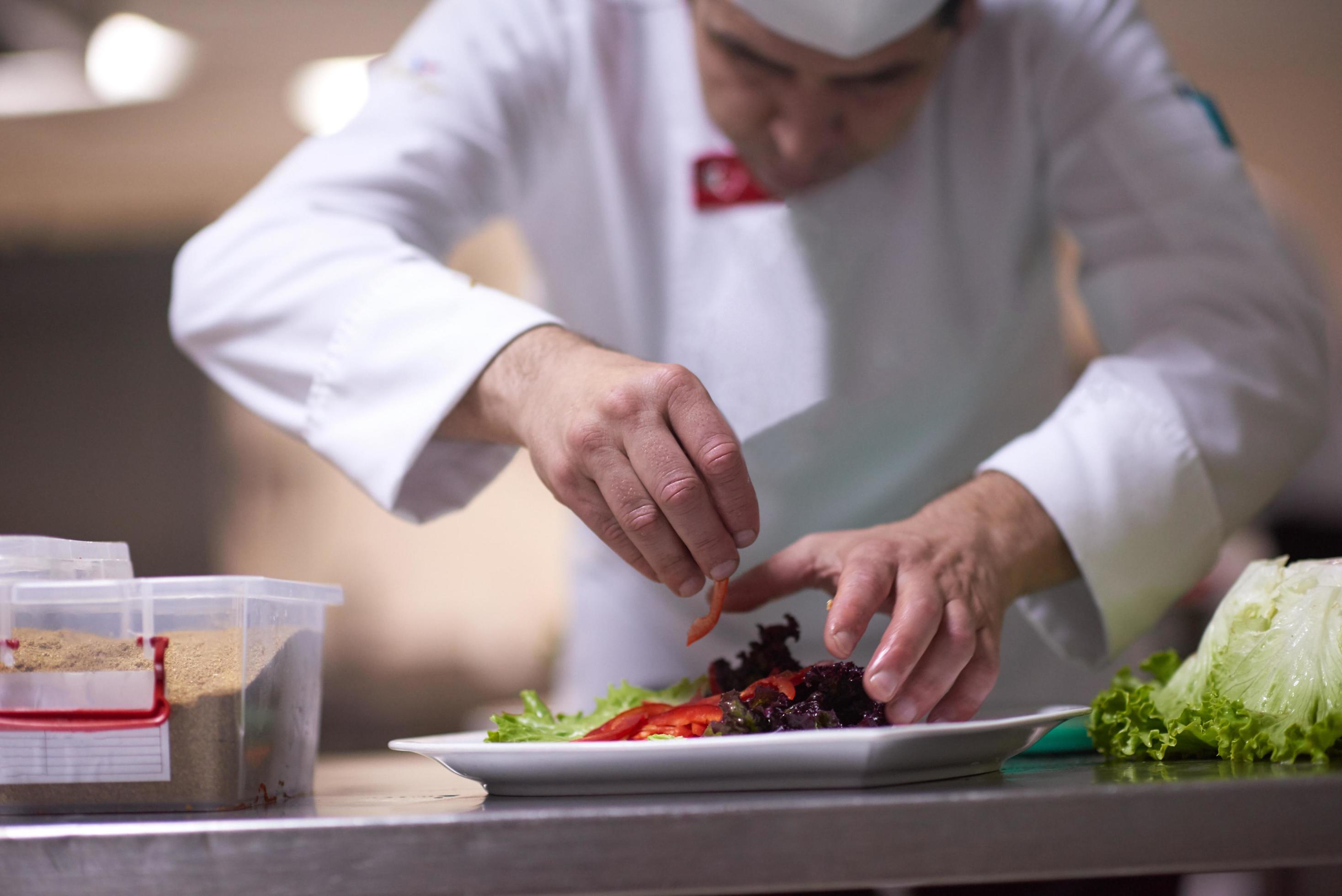 chef in hotel kitchen preparing and decorating food Stock Free