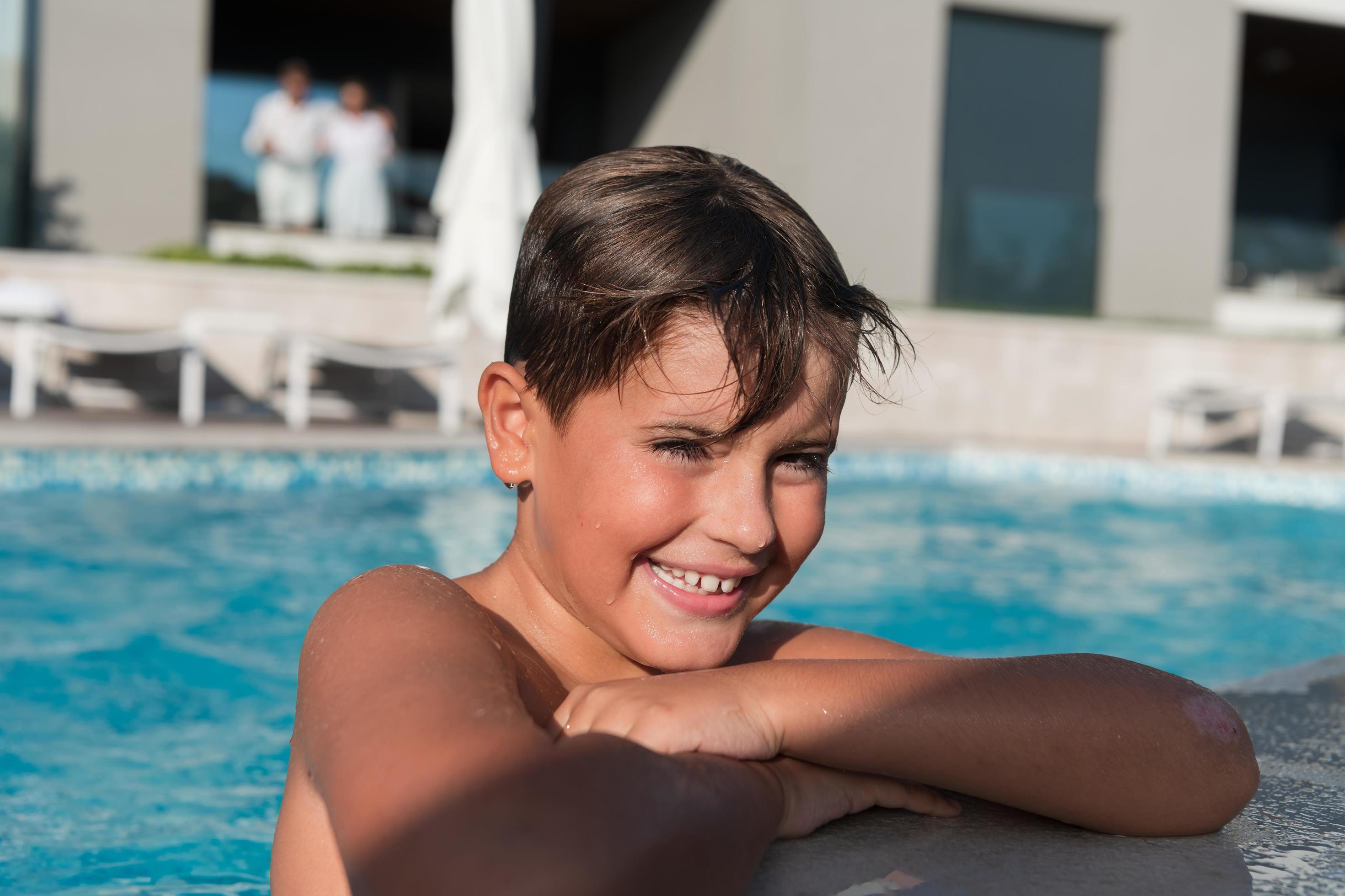 The boy enjoys a summer day swimming in the pool. The concept of a family vacation. Selective focus Stock Free