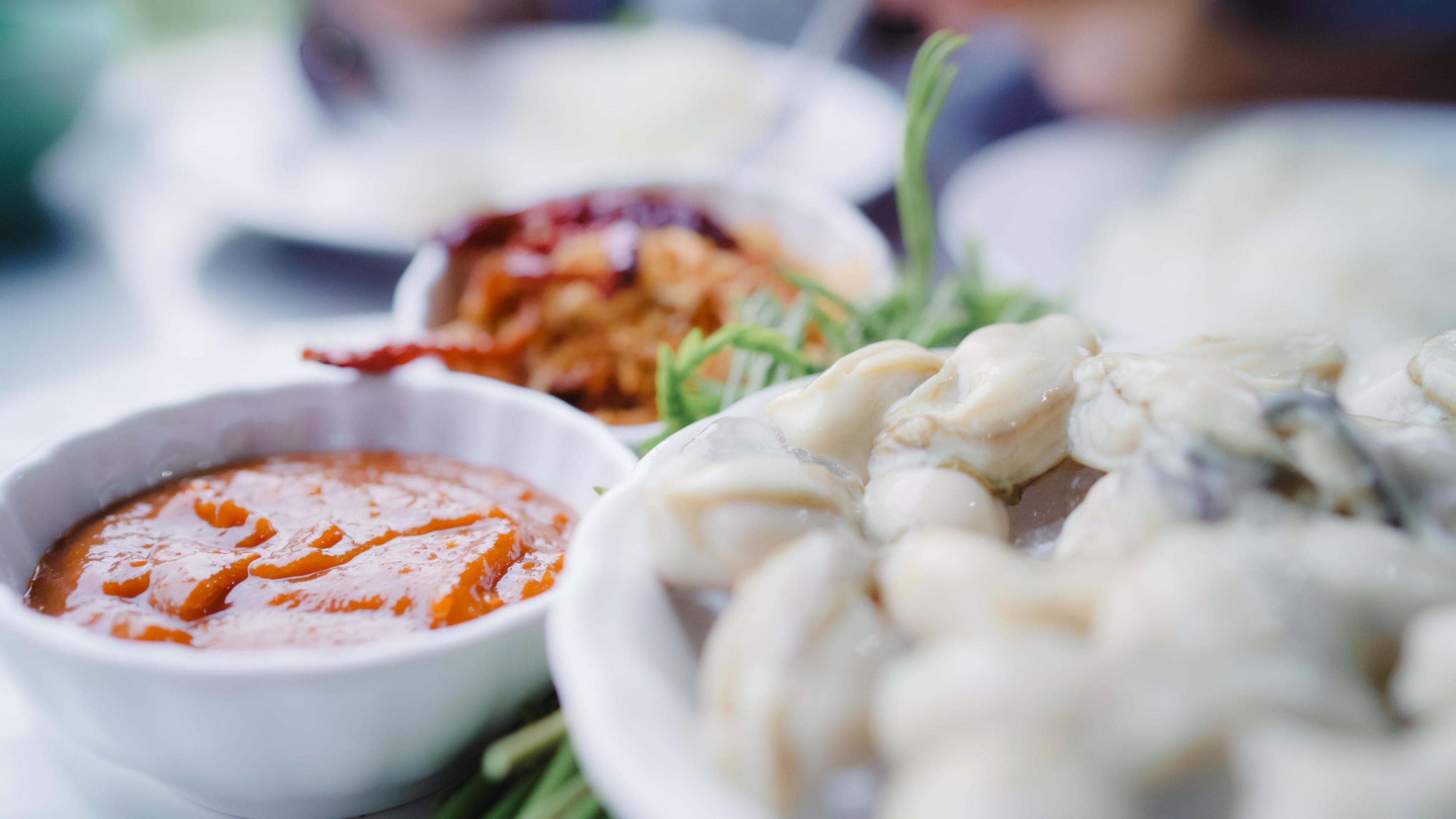 Young Asian woman eating oyster seafood in restaurant, teenager female feeling happy eating food. Women eating seafood concept. Stock Free