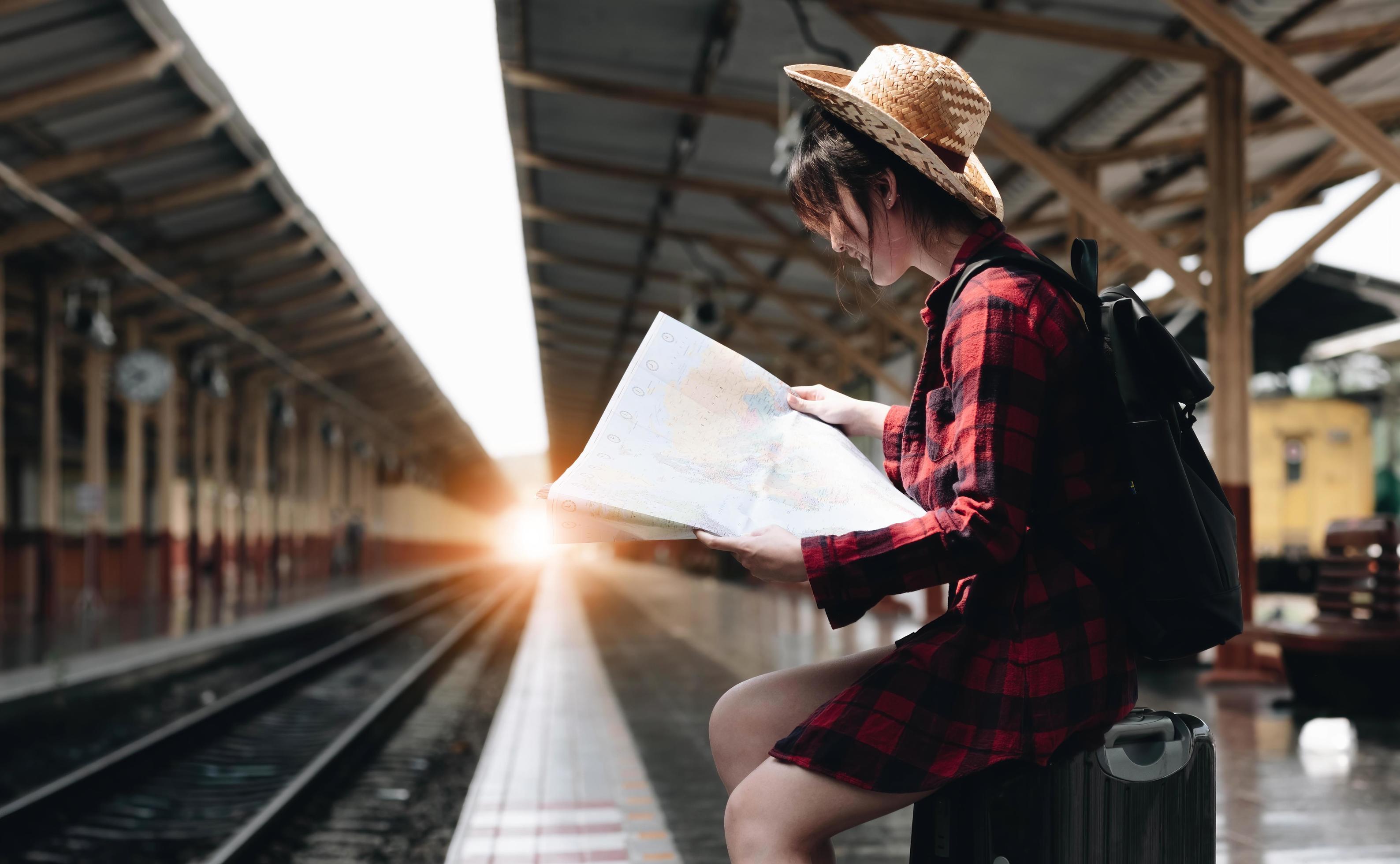 Young traveler woman looking on maps planning trip at train station. Summer and travel lifestyle concept Stock Free