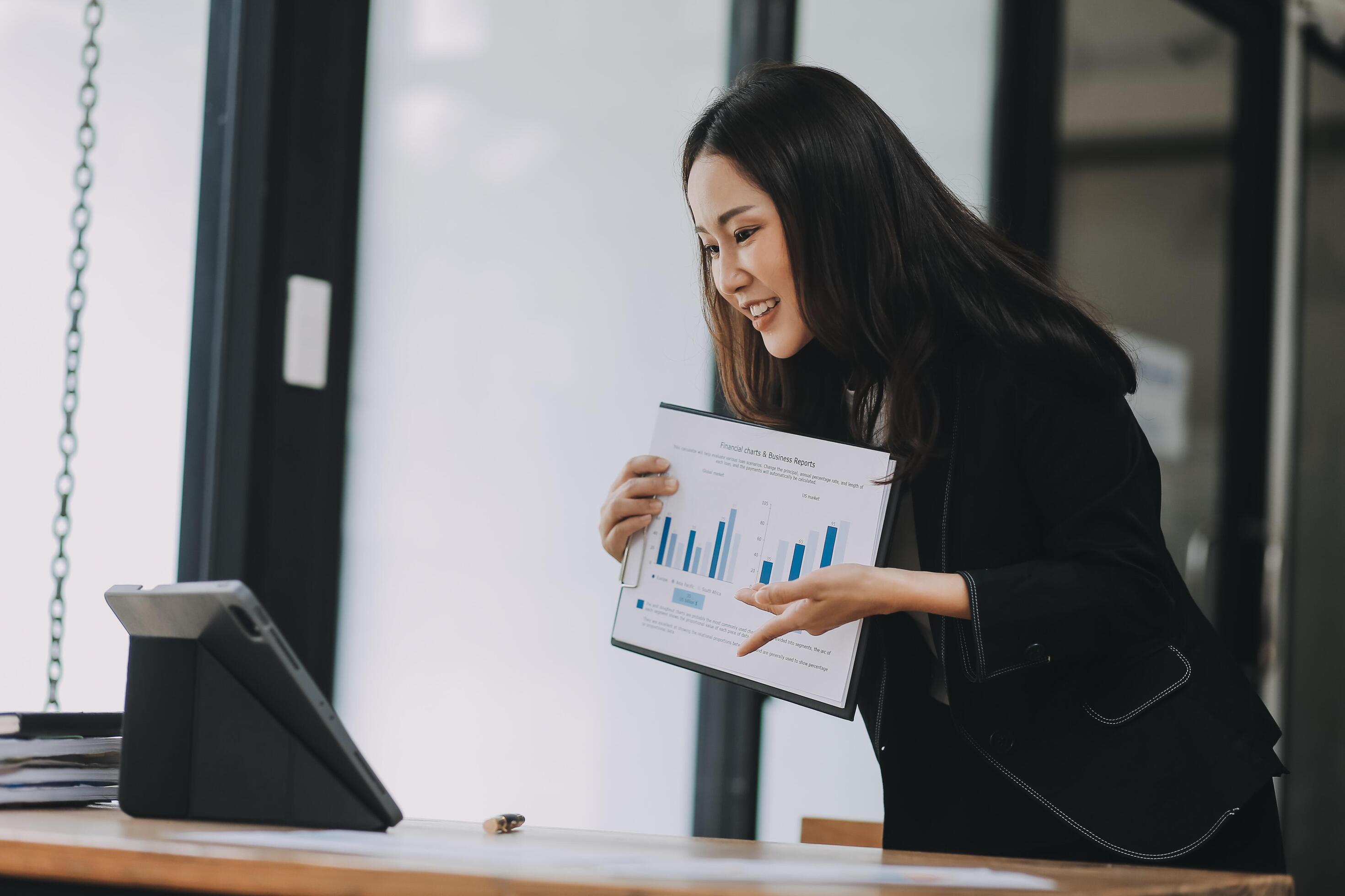 Pretty young Asian businesswoman working on laptop and taking notes In office. Stock Free