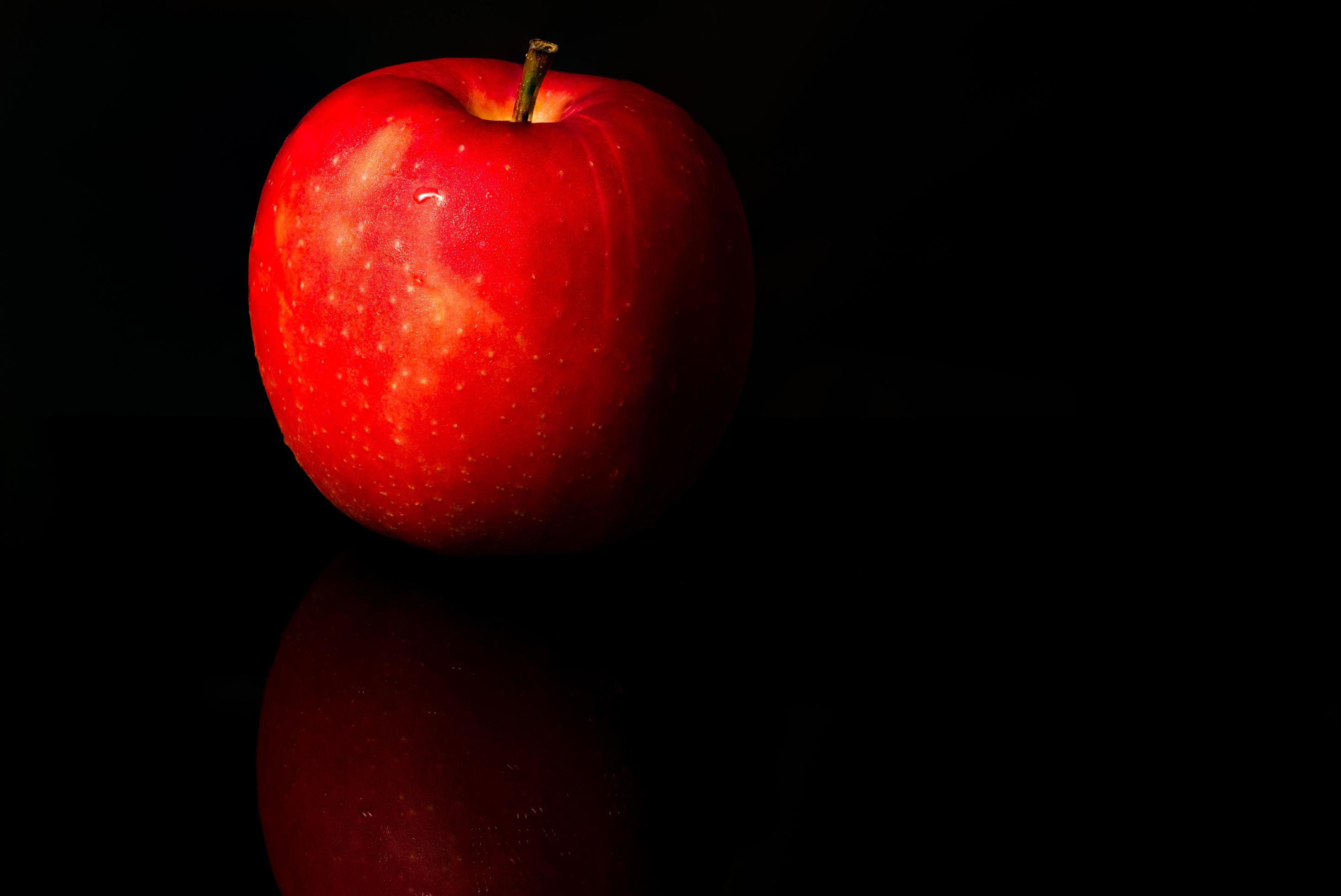 A red apple with water drops on skin isolated on black background with copy space. Healthy fruit and healthy food concept. Vegan food. Stock Free