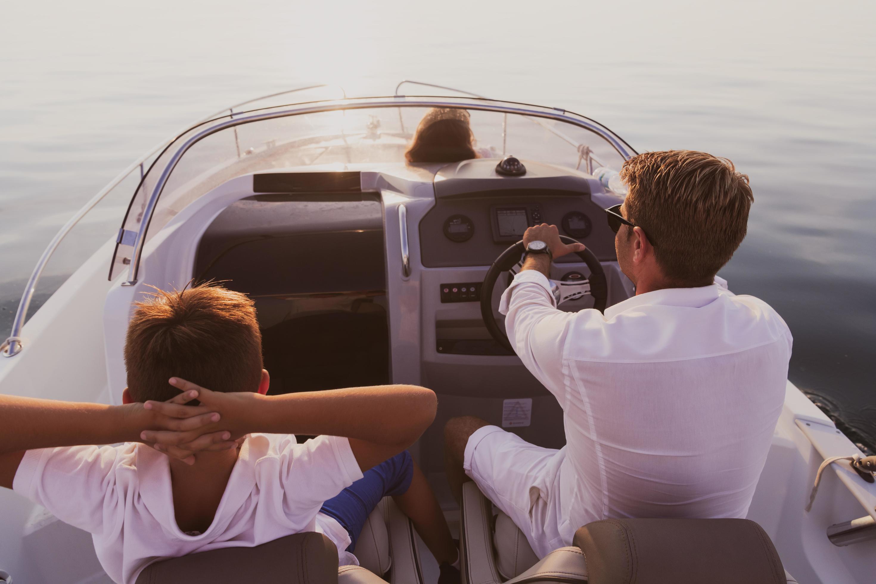 A senior couple in casual outfits with their son enjoy while riding a boat at sea at sunset. The concept of a happy family. Selective focus Stock Free