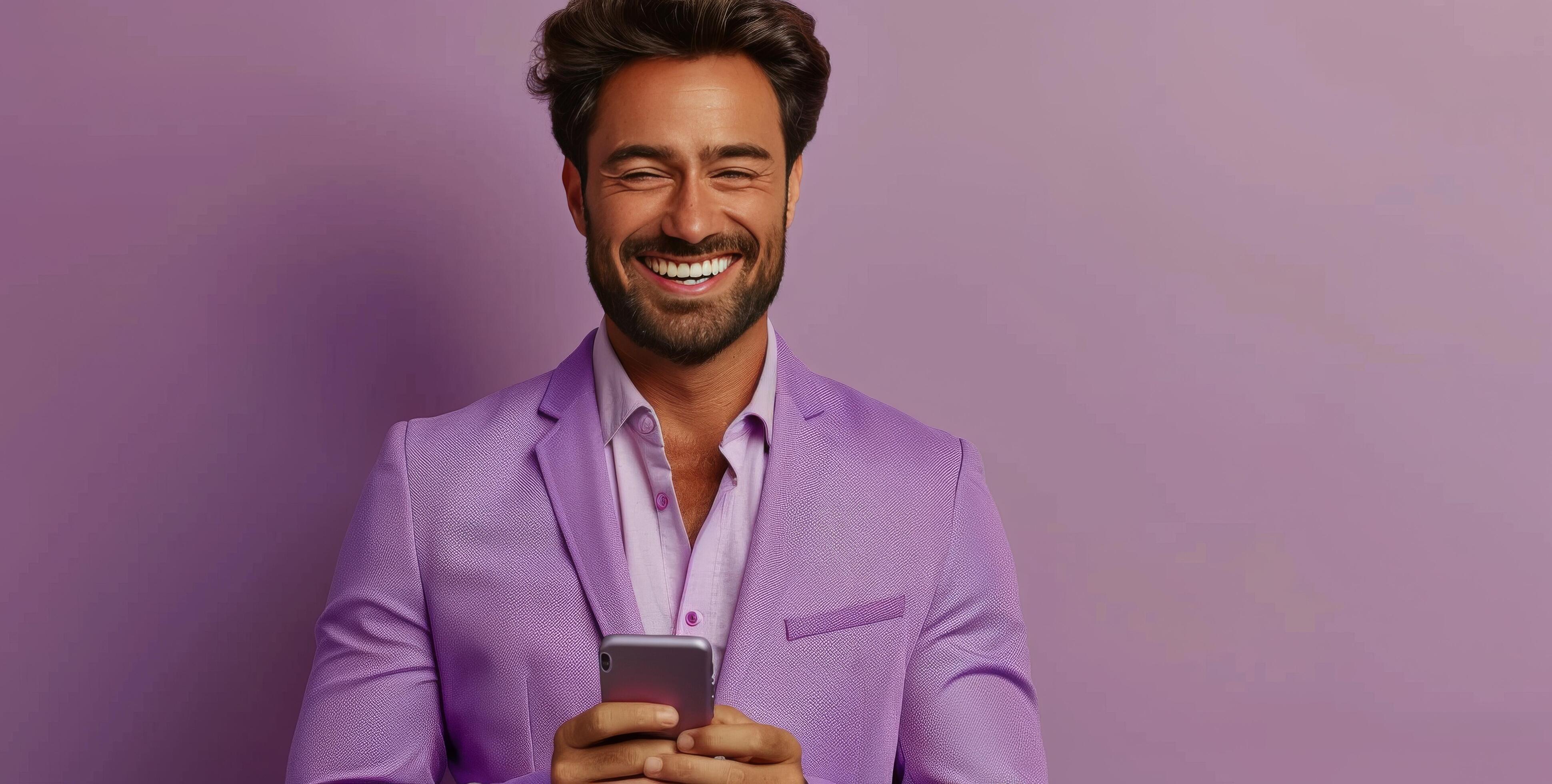 Smiling Man in Purple Suit Uses Smartphone Against Purple Background Stock Free