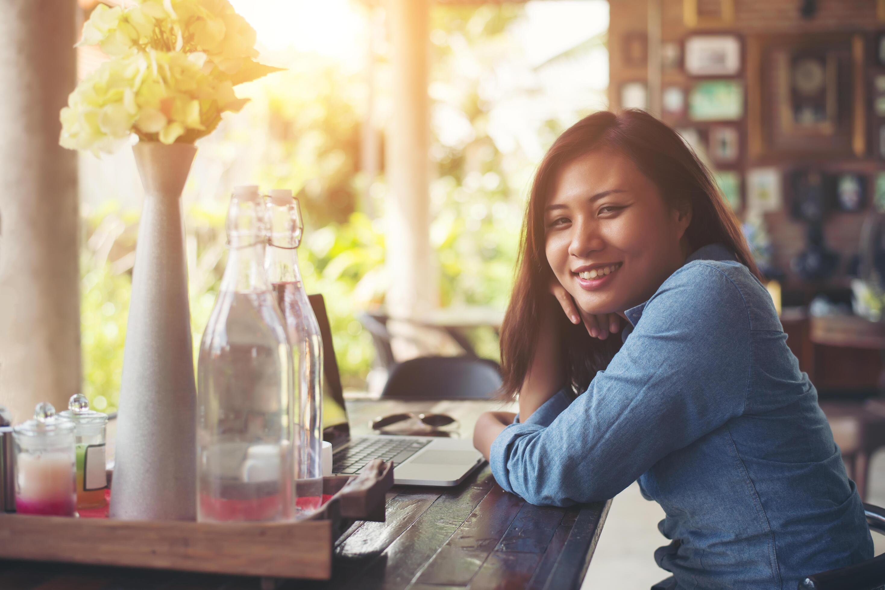 Young hipster woman with coffee and laptop. Portrait of beautiful smiling woman sitting in a cafe, Relaxing. Woman lifestyle concept. Stock Free