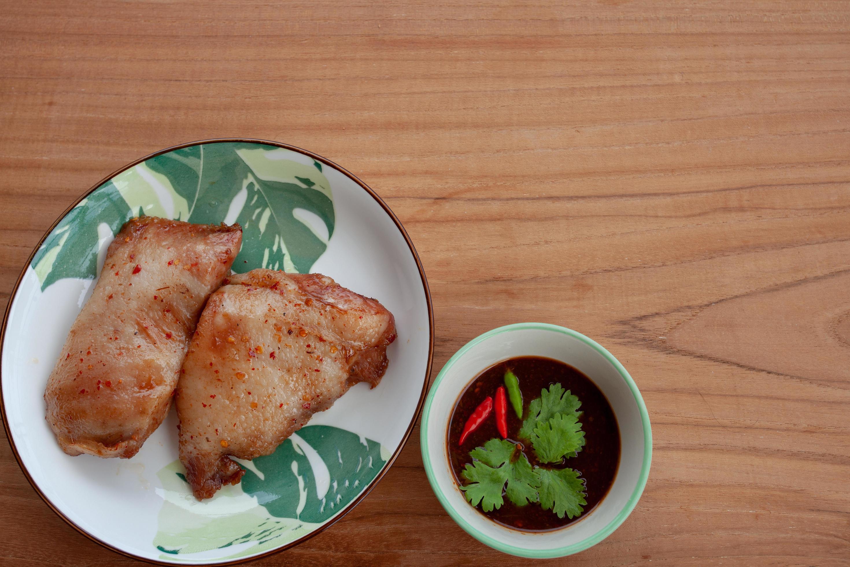 Roast pork and Thai Dipping Spicy Sauce on wooden table.Thailand street food. Stock Free