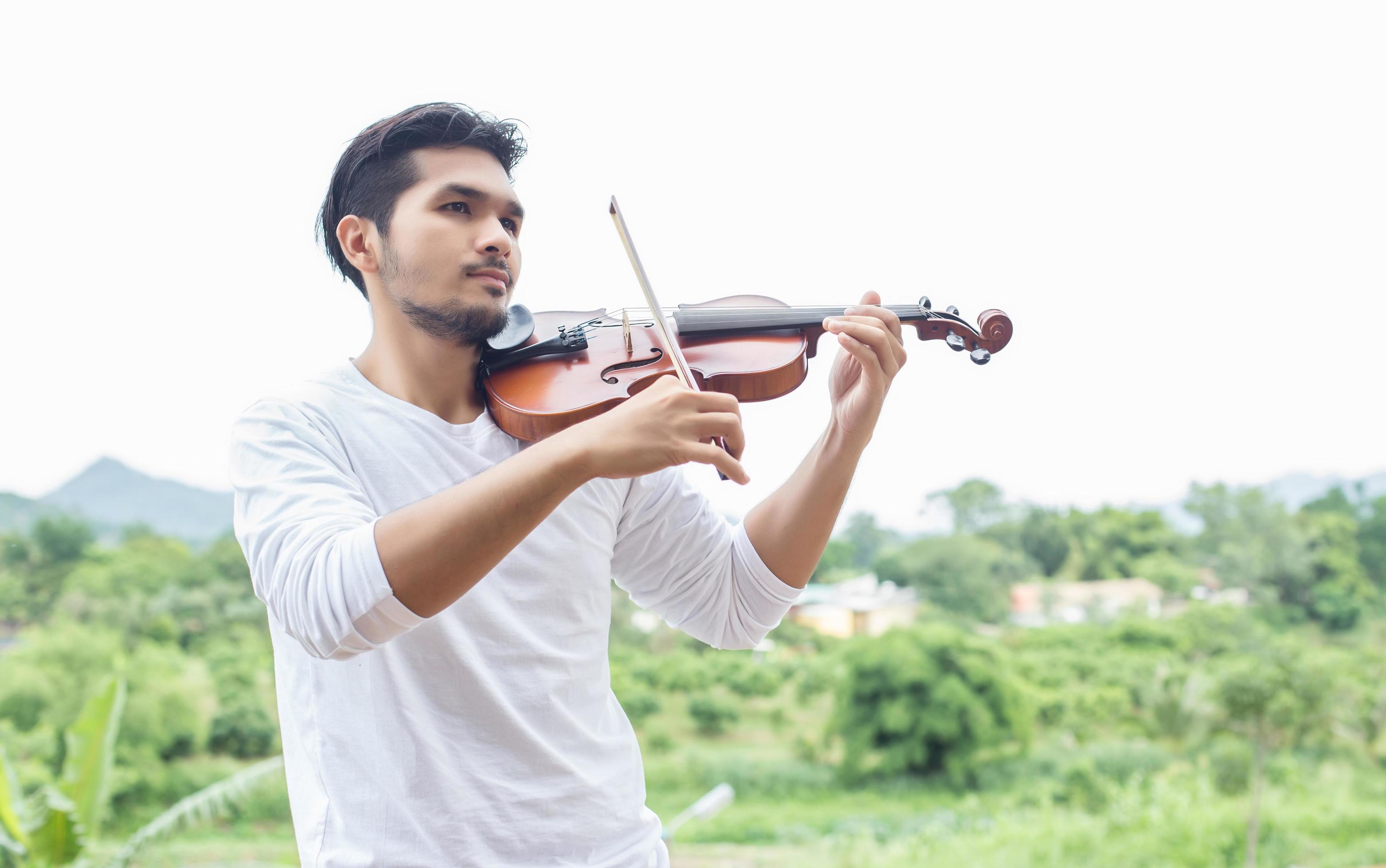 Young hipster musician man playing violin in the nature outdoor lifestyle behind mountain. Stock Free