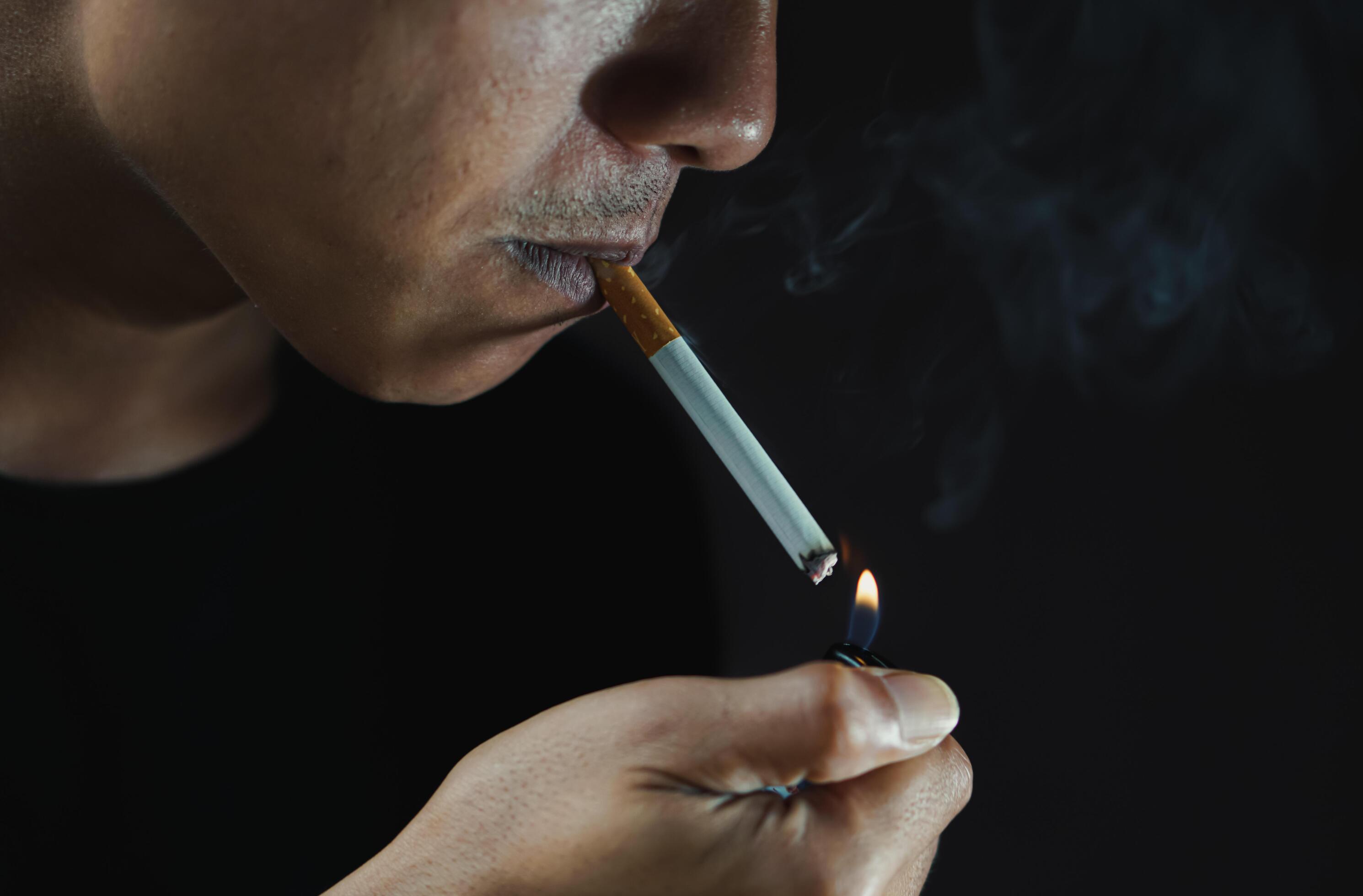 A man smoking cigarette in dark room Stock Free