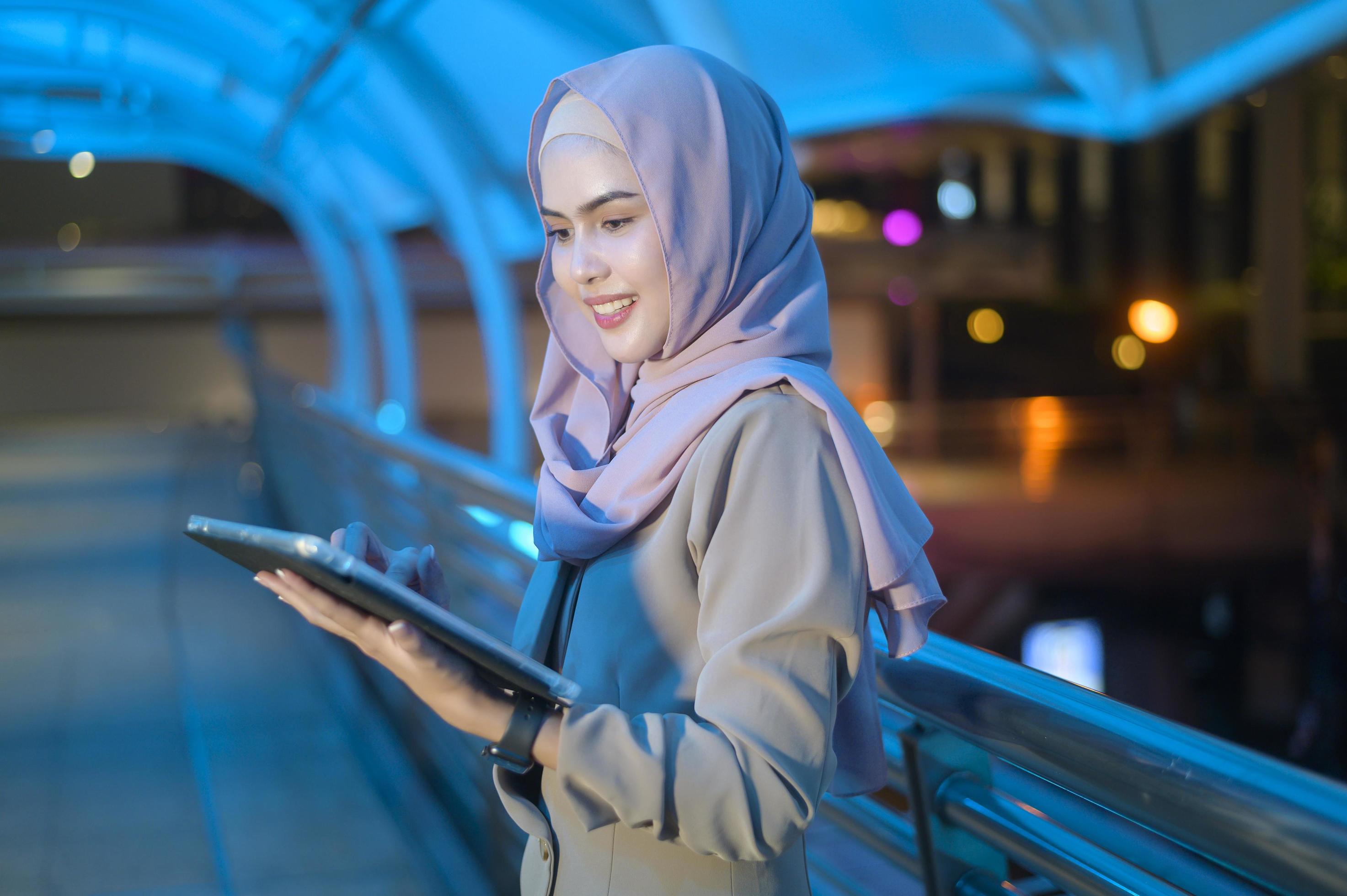 A young Muslim Businesswoman is using tablet computer in modern City at night , Business technology lifestyle concept Stock Free