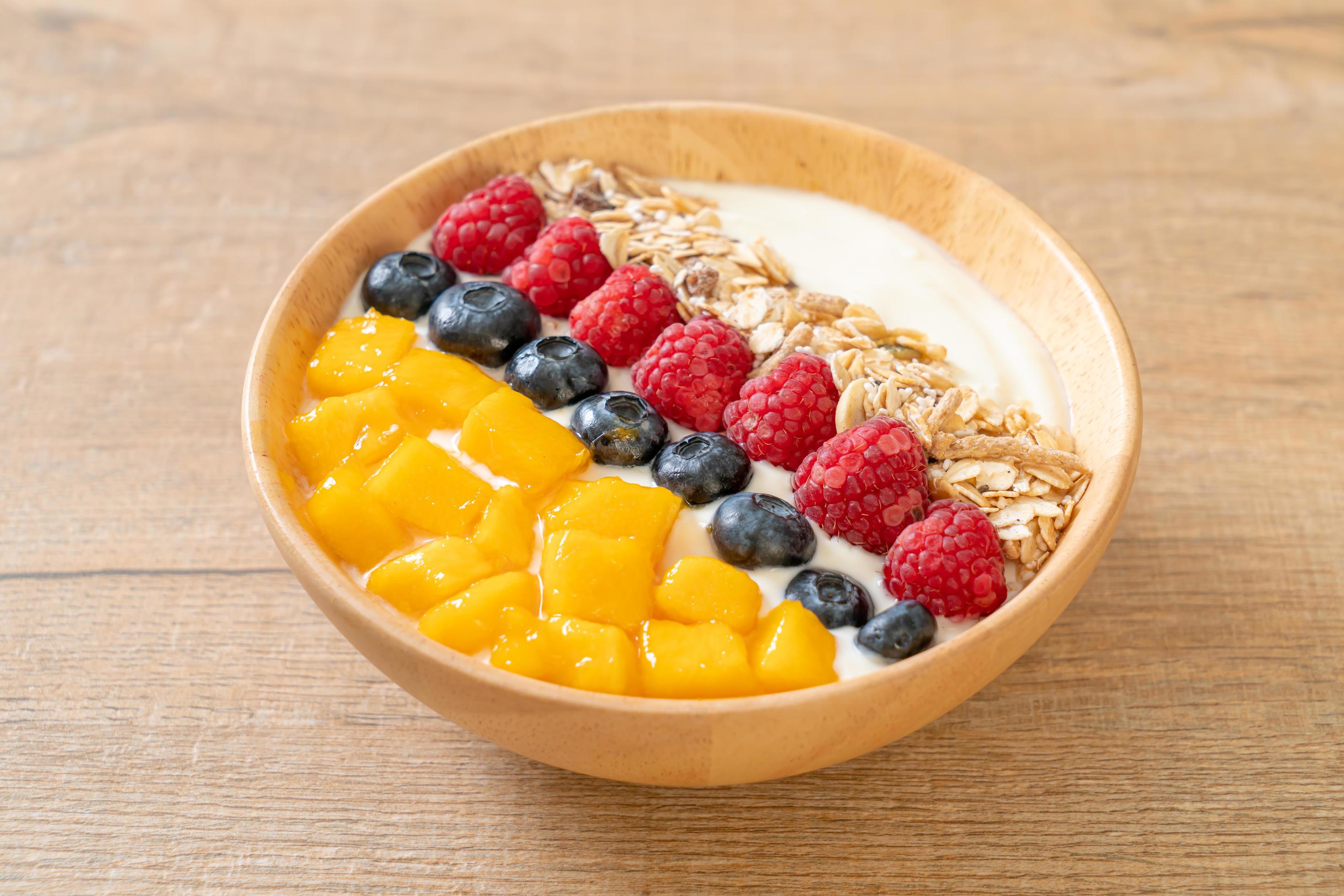 Homemade yogurt bowl with raspberry, blueberry, mango, and granola – healthy food style Stock Free