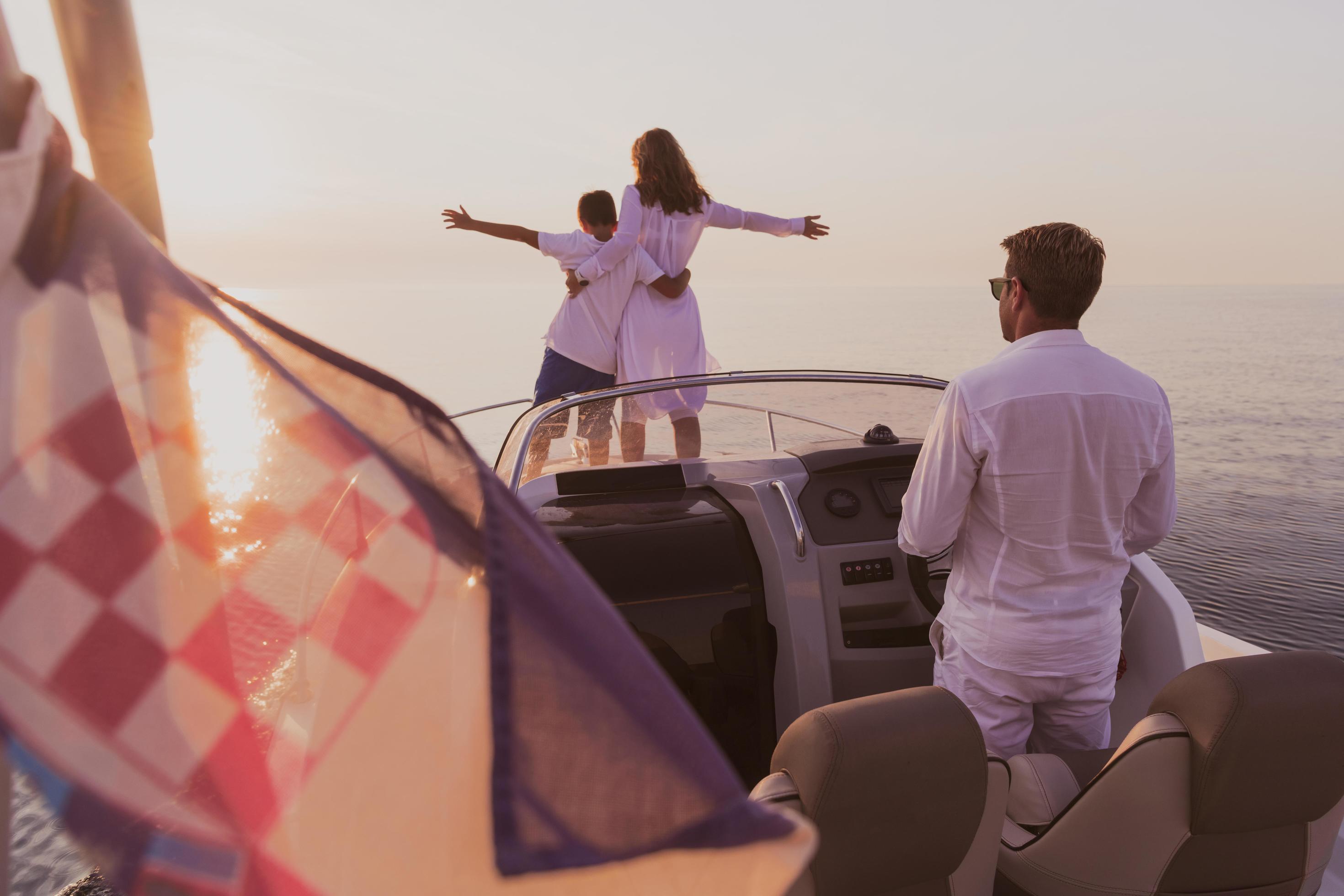 A senior couple in casual outfits with their son enjoy while riding a boat at sea at sunset. The concept of a happy family. Selective focus Stock Free