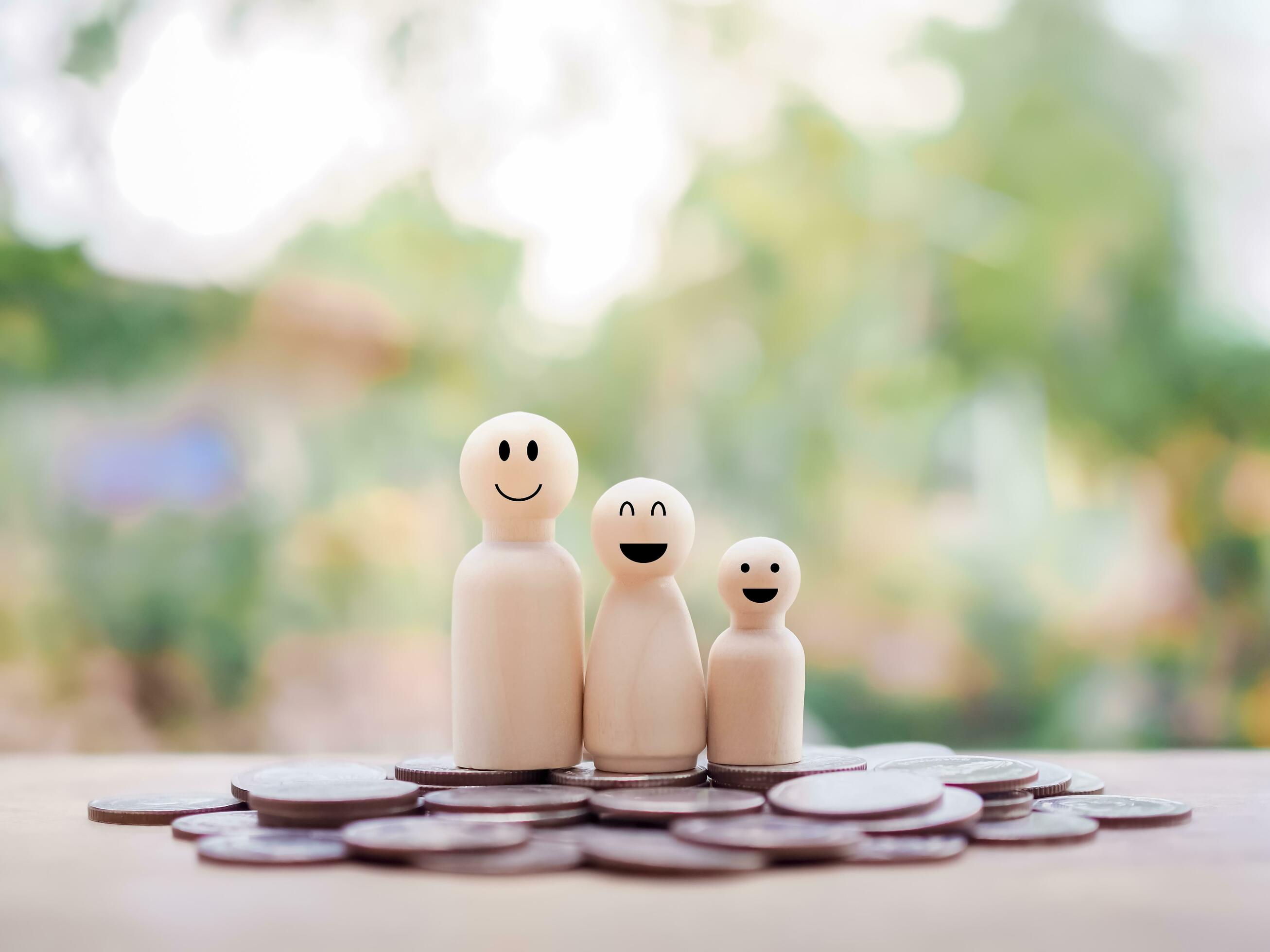 Wooden figure of the family standing on stack of coins for business concept Stock Free