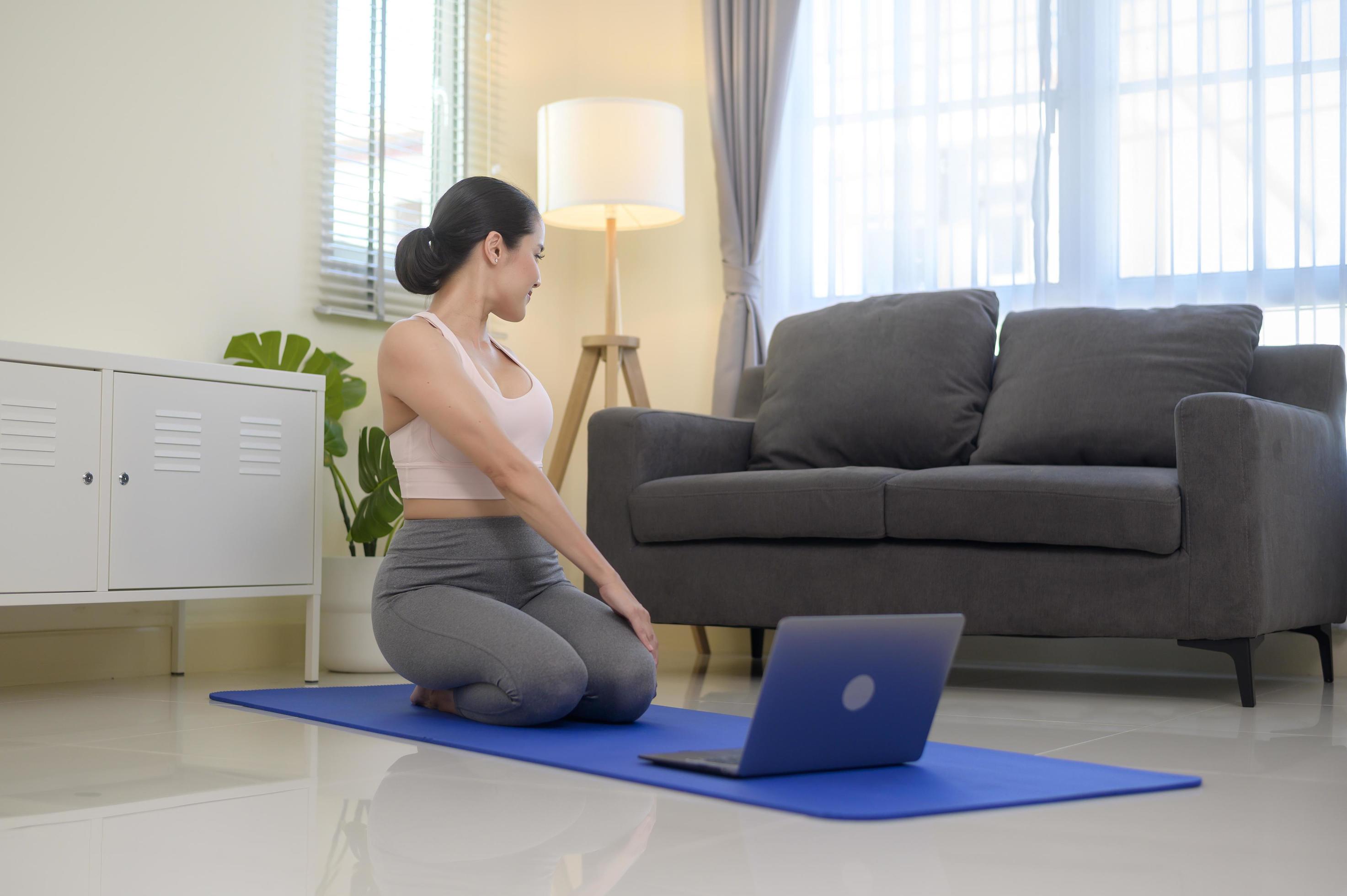 Fit young woman practicing yoga at home via online class with professional instructor, sport and healthy lifestyle concept. Stock Free