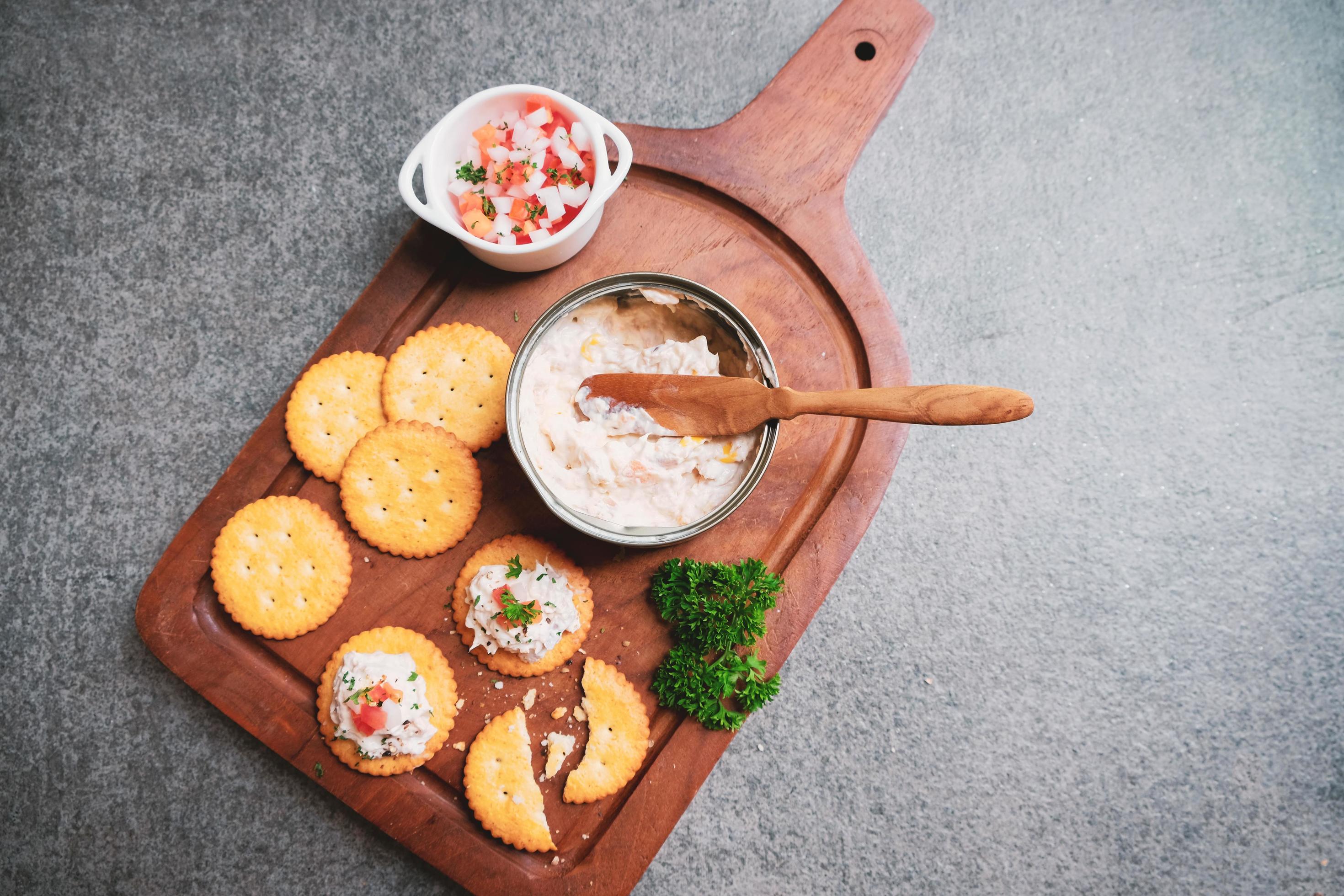 Top view of tasty tuna spread with crackers on wooden tray and black stone background with copy space, healthy food and appetize concept Stock Free