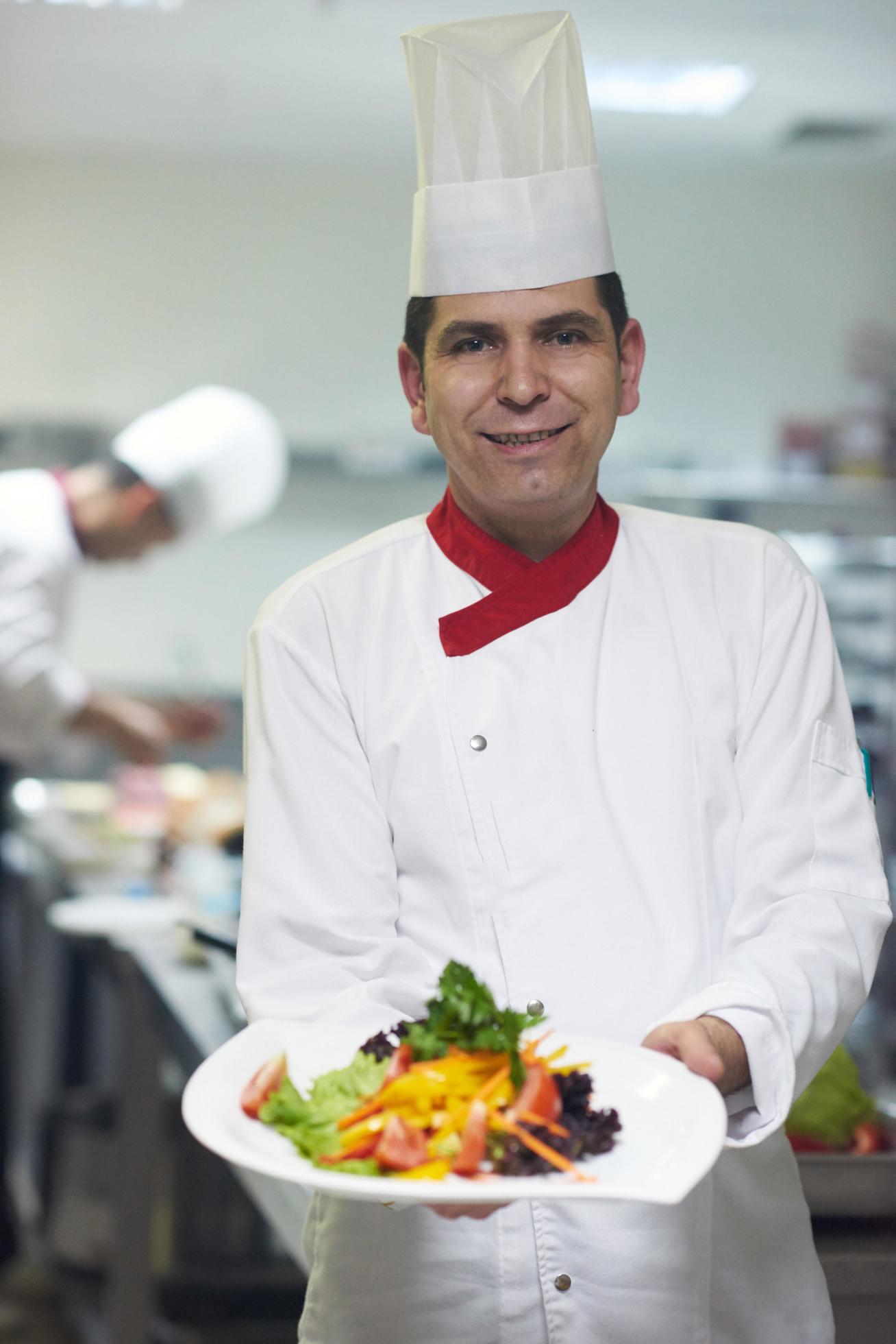 chef in hotel kitchen preparing and decorating food Stock Free