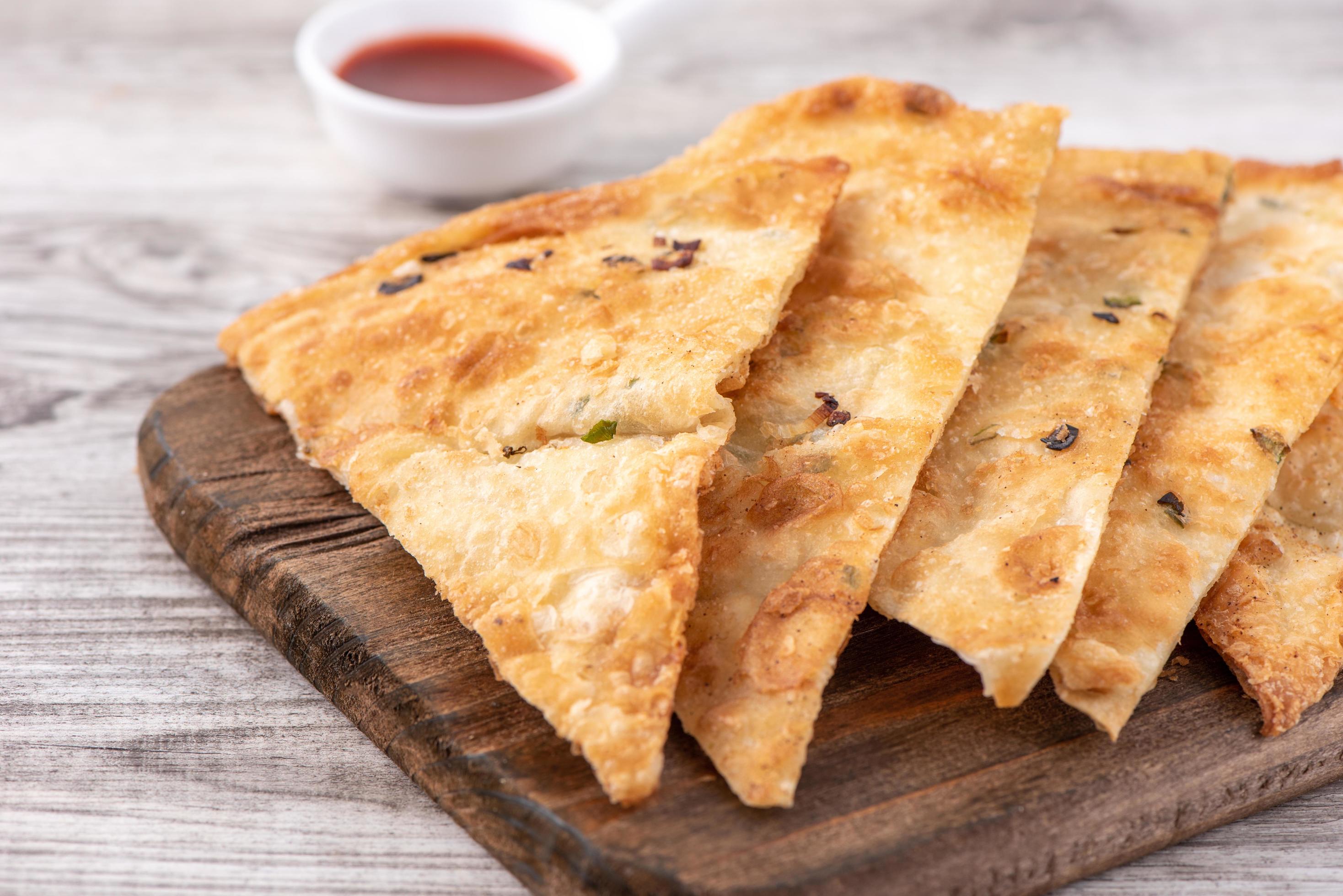 Taiwanese food – delicious flaky scallion pie pancakes on bright wooden table background, traditional snack in Taiwan, close up. Stock Free