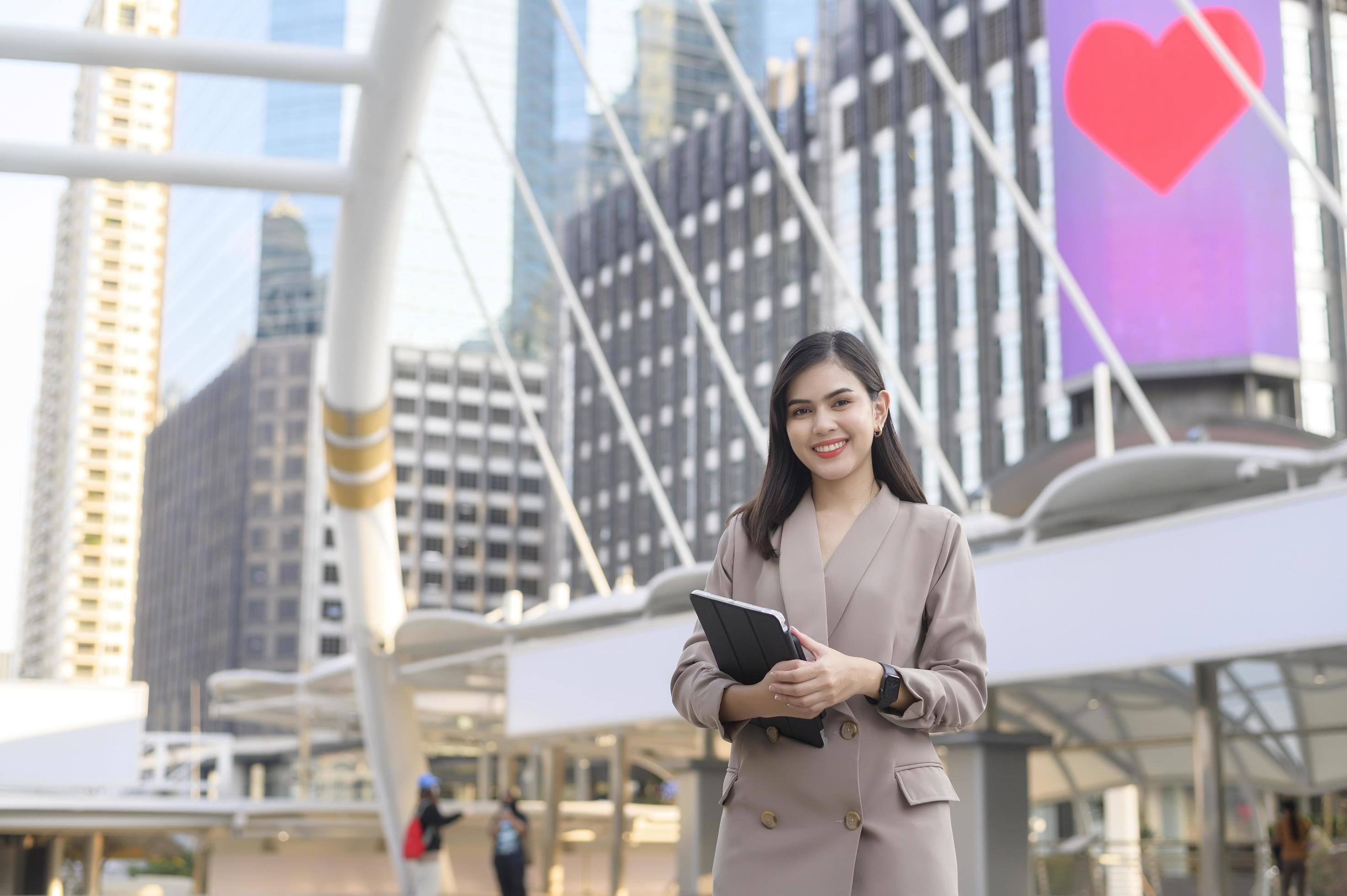 A young beautiful businesswoman is using tablet in Modern city , business technology , city lifestyle concept Stock Free