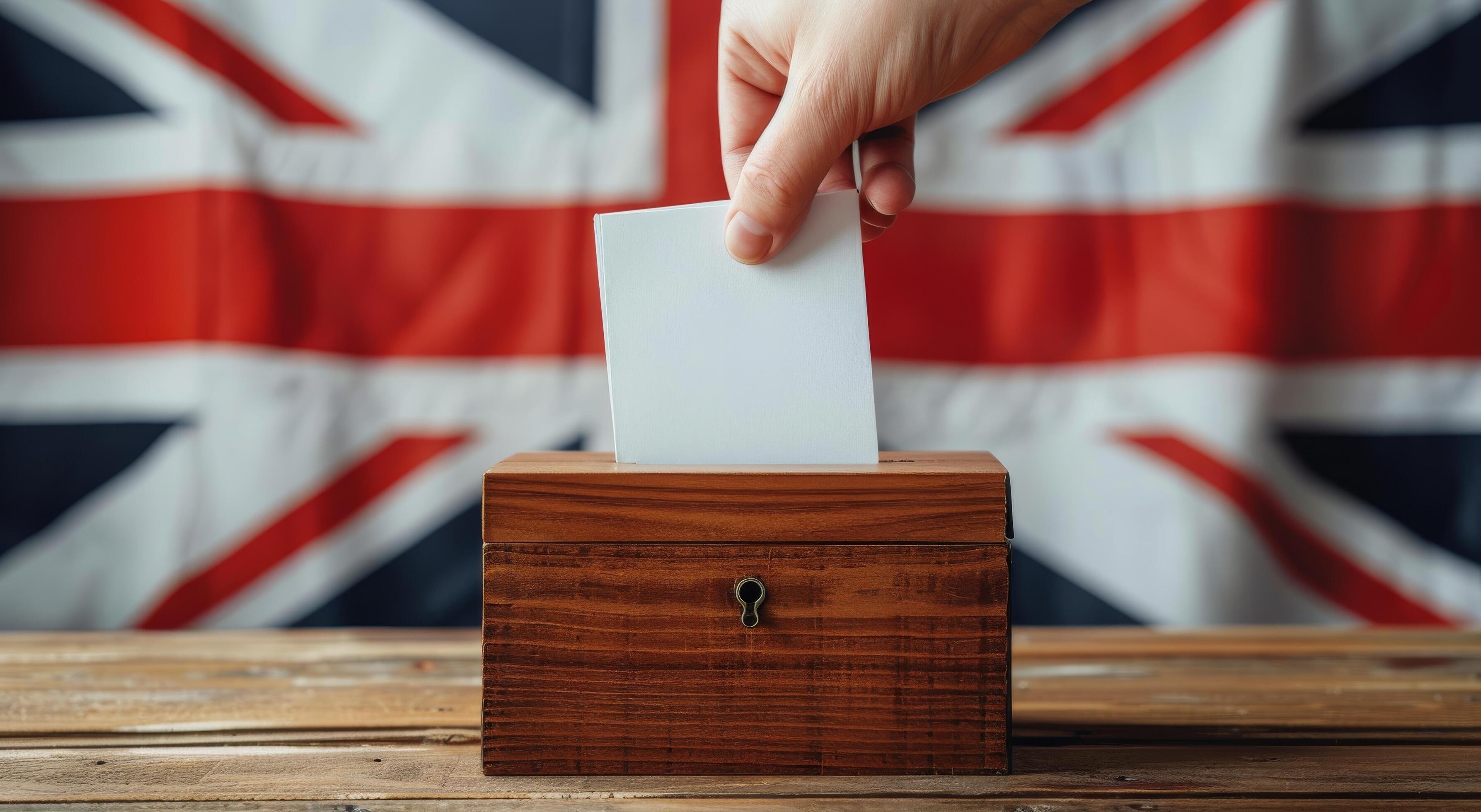 Hand Placing Ballot in Wooden Box With UK Flag Background Stock Free