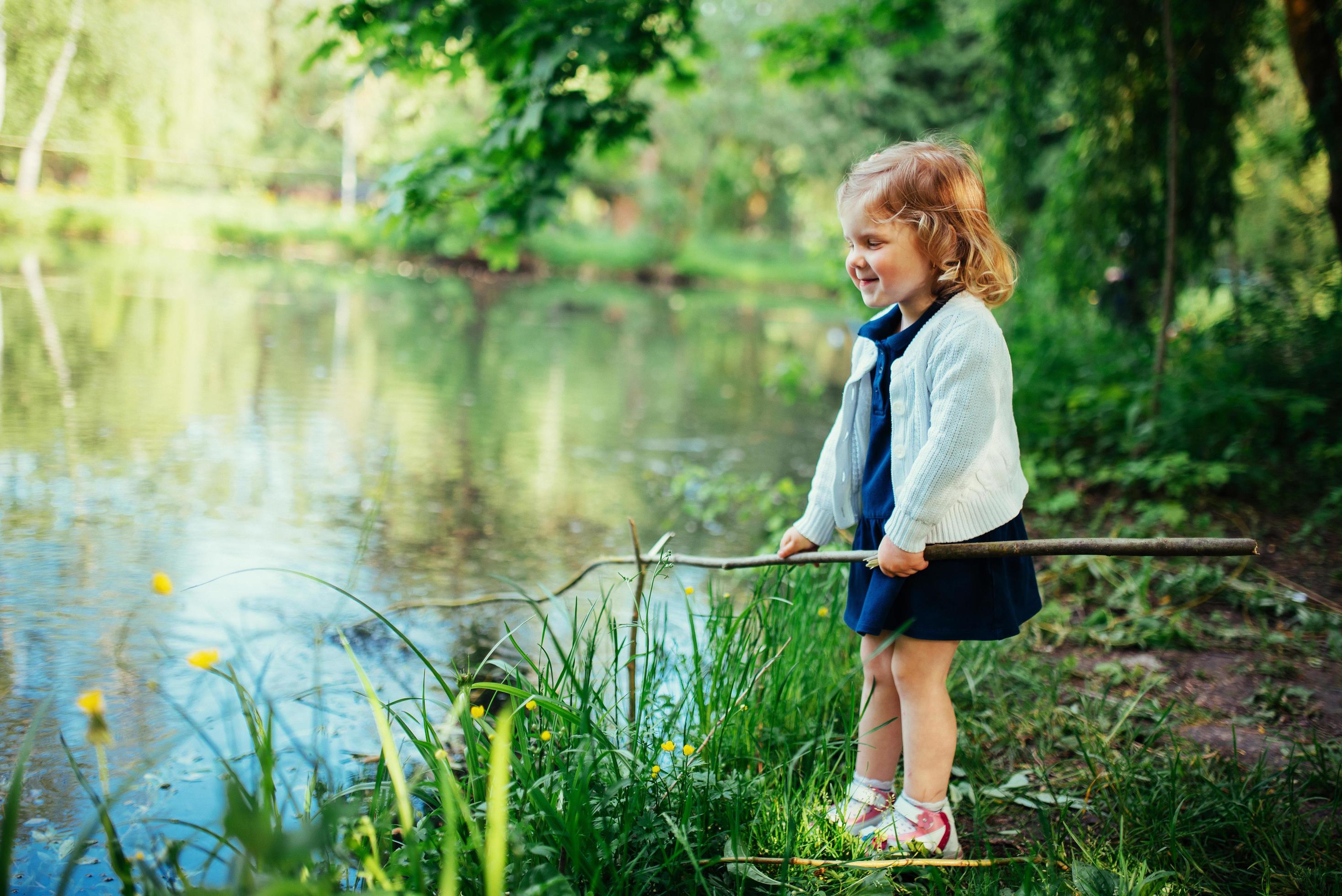 Cute little blonde girl is against the background of water and g Stock Free