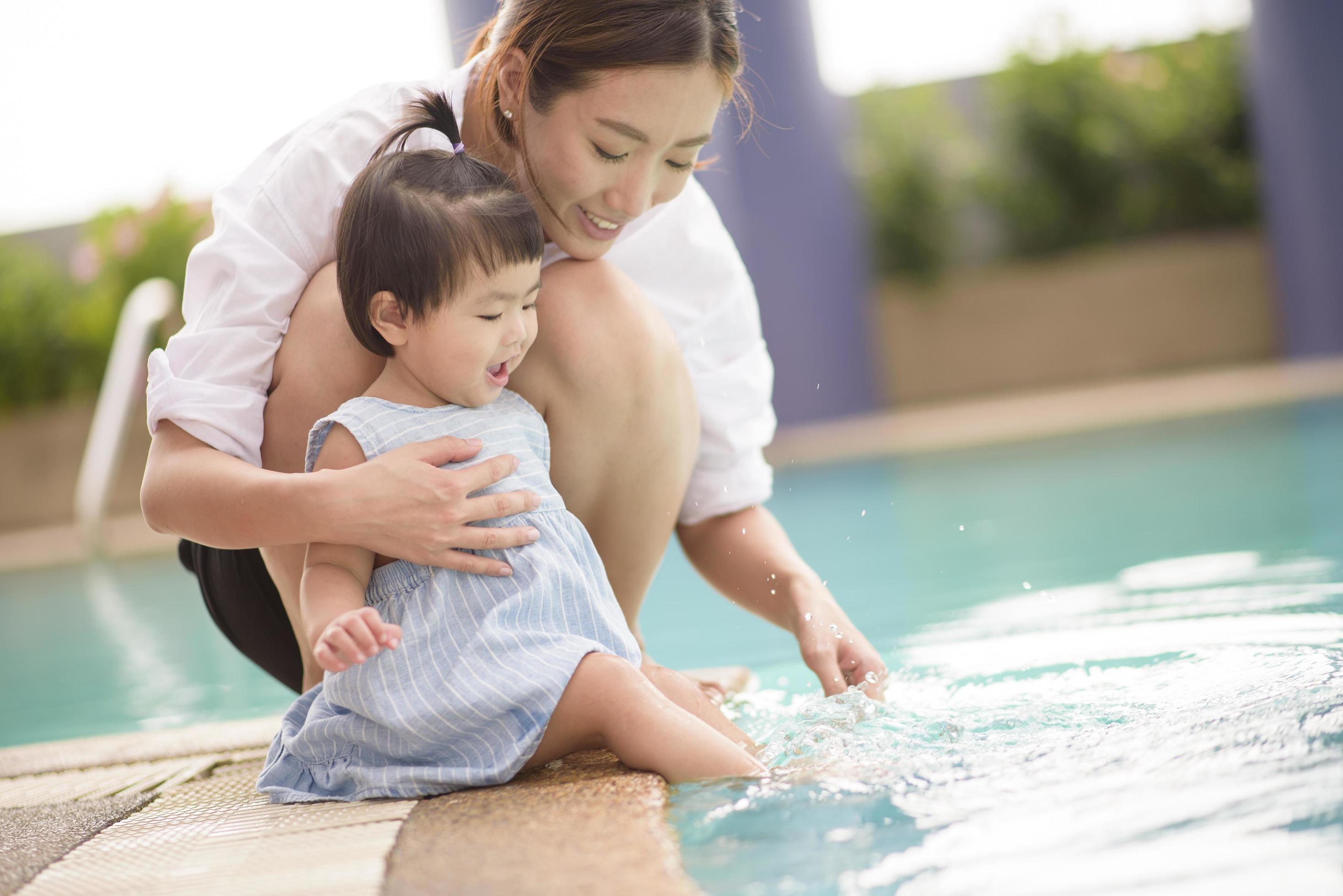 A Happy Asian mother and daughter are enjoy swimming in pool , lifestyle, parenthood, family concept Stock Free