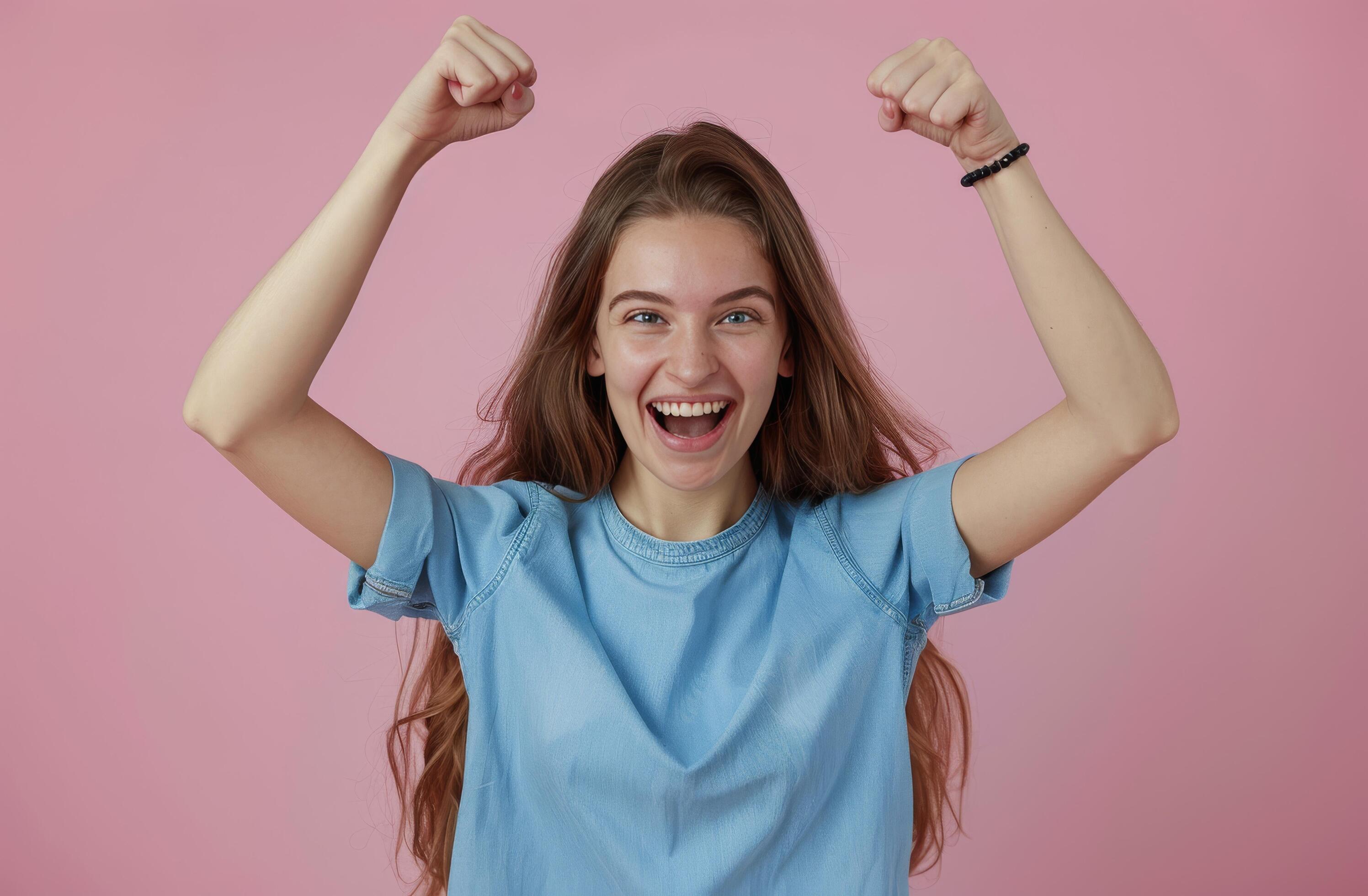 Happy Woman With Long Brown Hair Raises Her Fists in Victory on Pink Background Stock Free