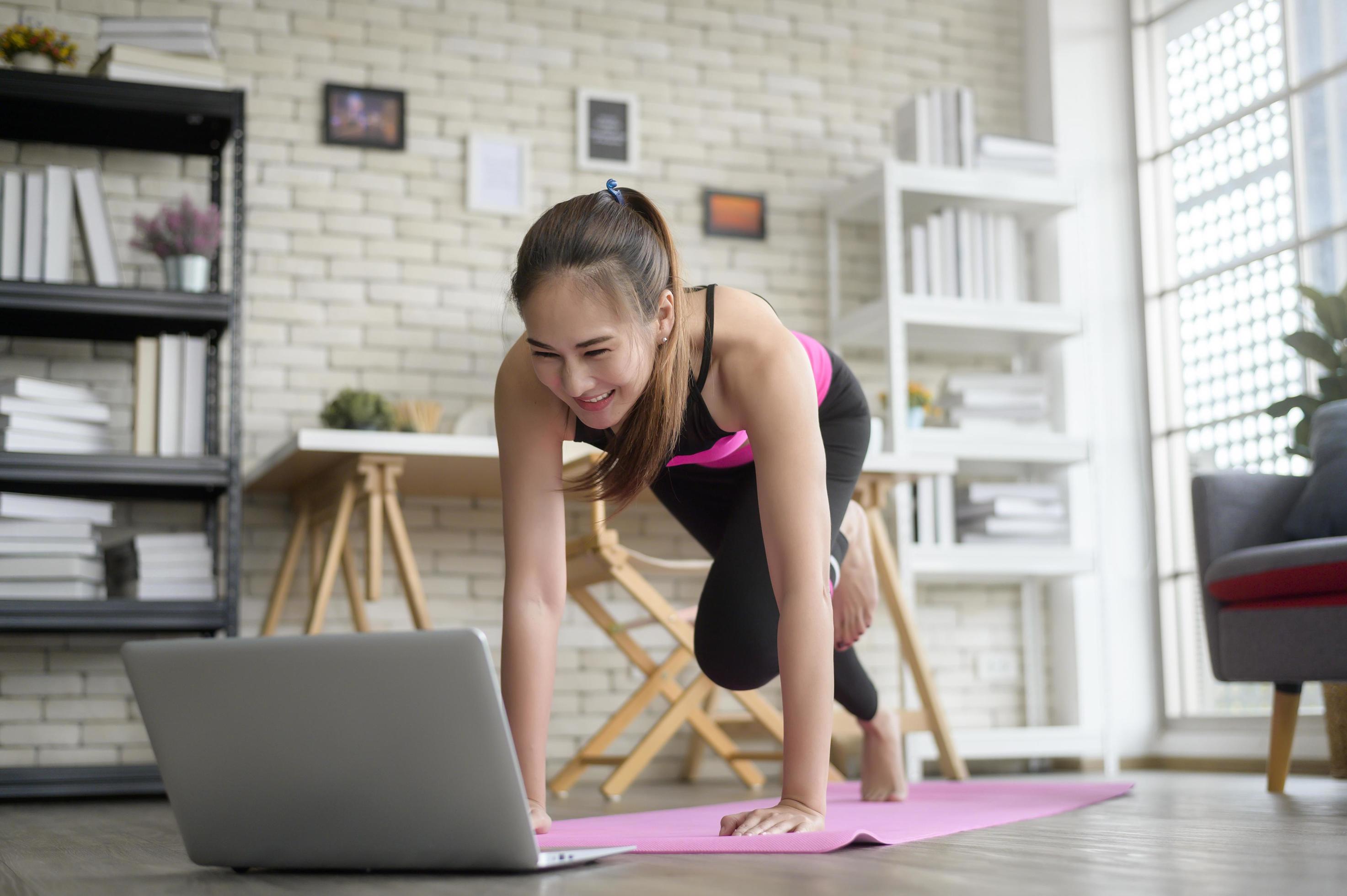 Fit young woman practicing yoga at home via online class with professional instructor, sport and healthy lifestyle concept. Stock Free