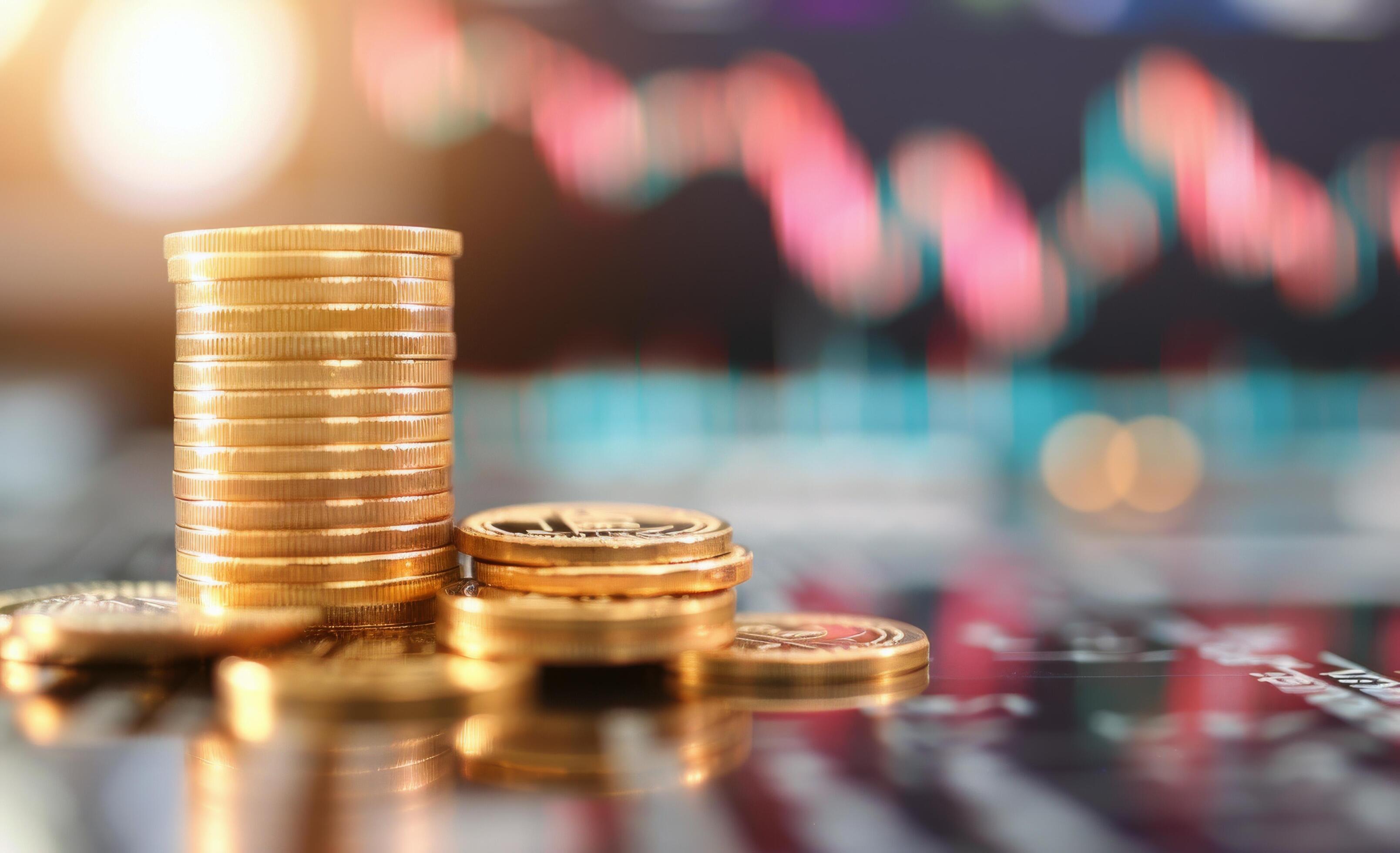 Stacked Gold Coins on Dark Background With Financial Graph in Soft Focus Stock Free