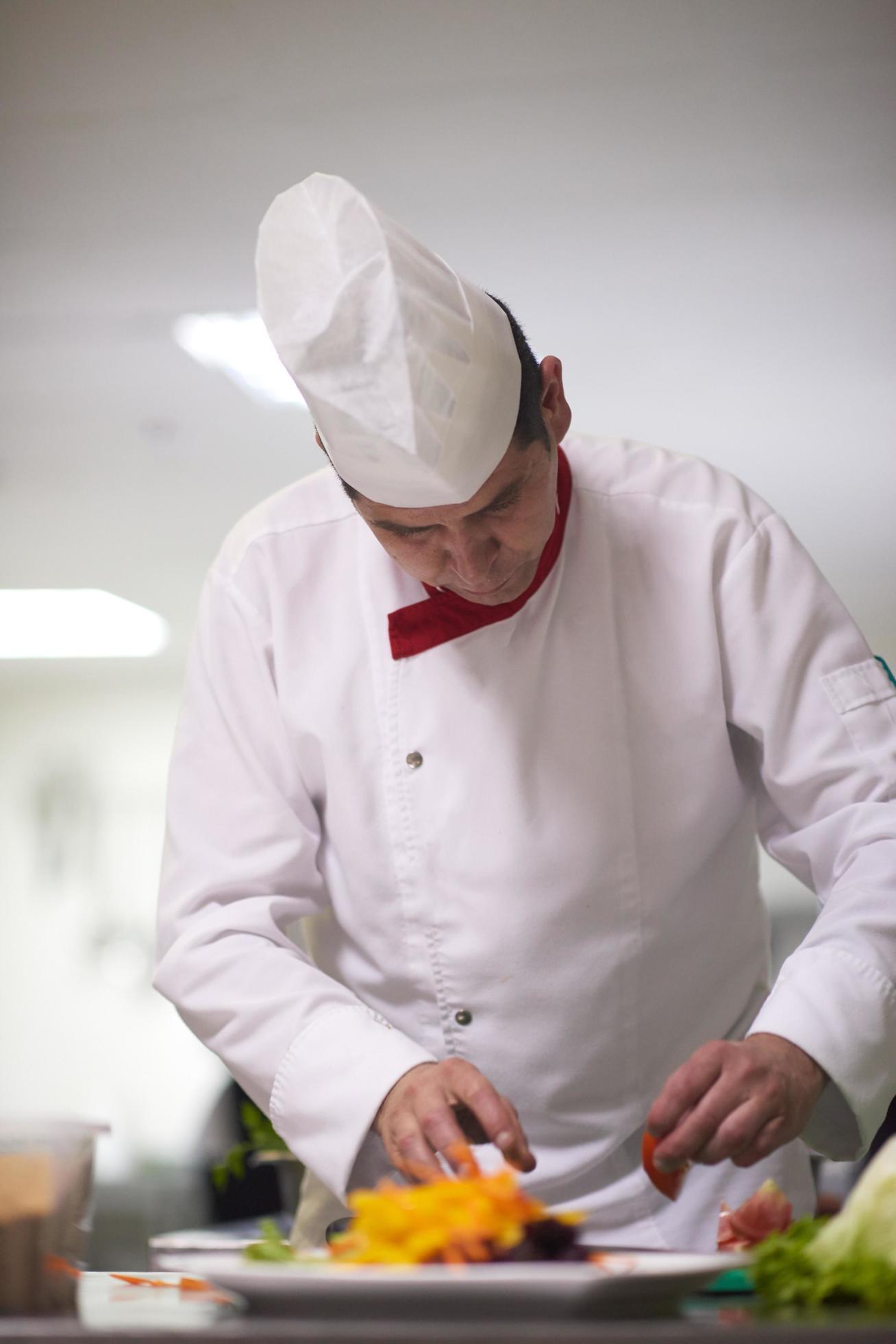 chef in hotel kitchen preparing and decorating food Stock Free