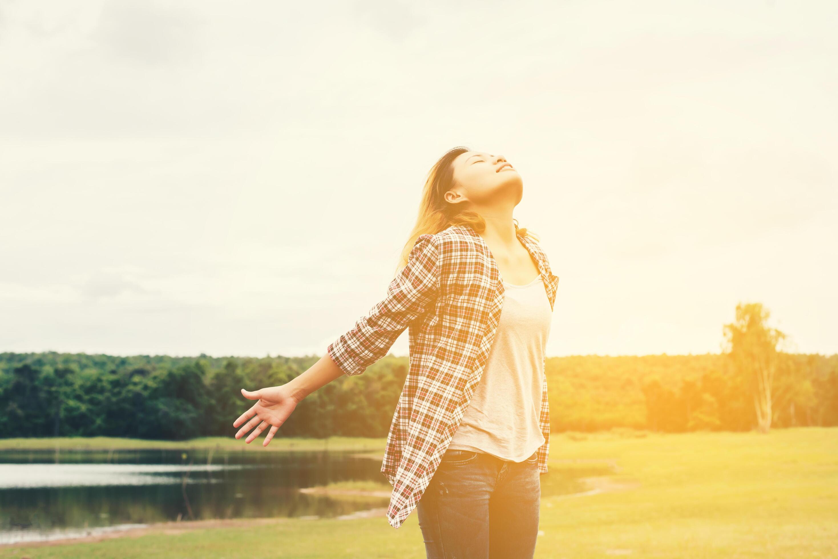 Woman lifestyle concept young beautiful woman stretching hands in the air enjoy with fresh air outside nature. Stock Free