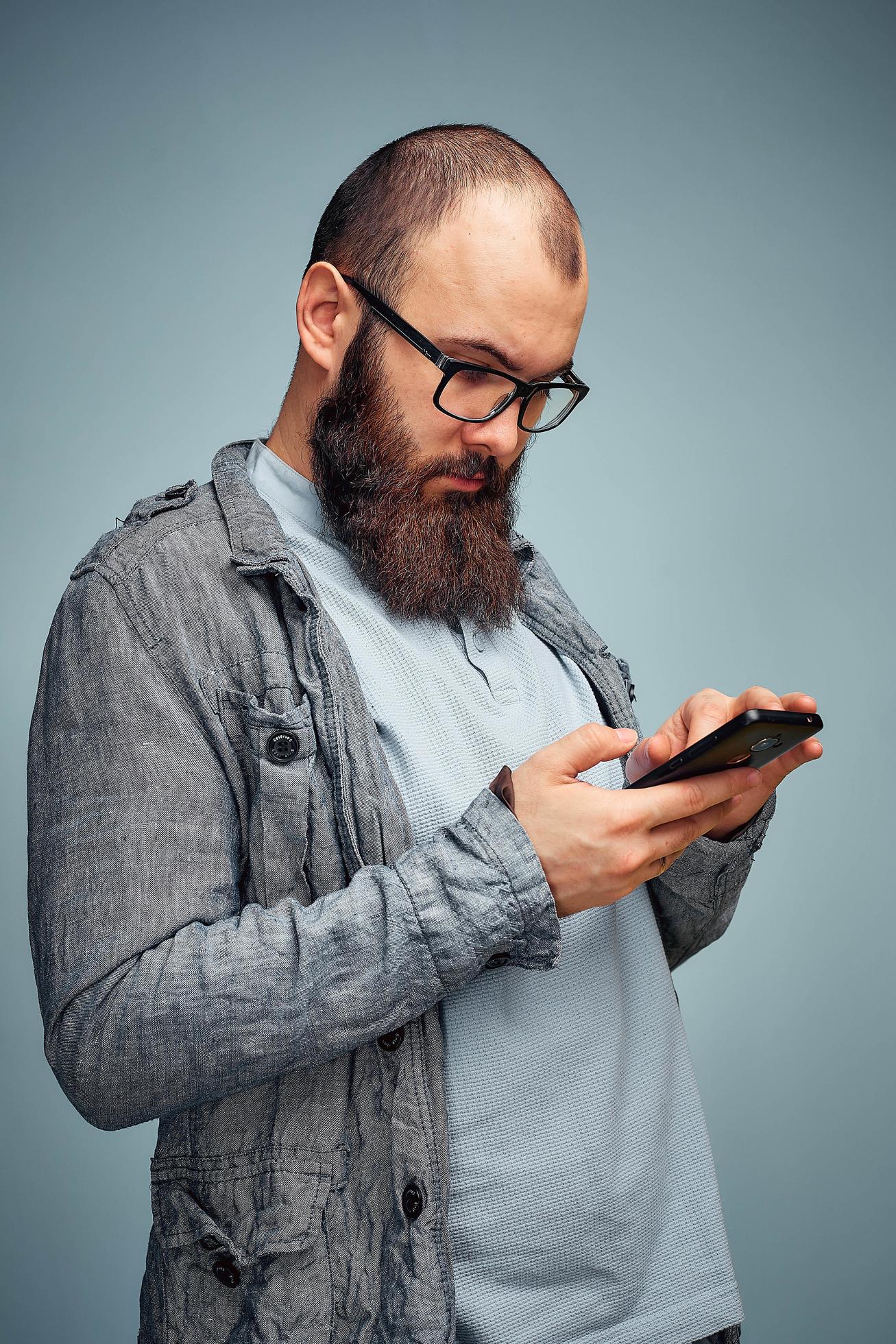 lifestyle brooding man with a beard and a telephone, background, copyspace. Stock Free