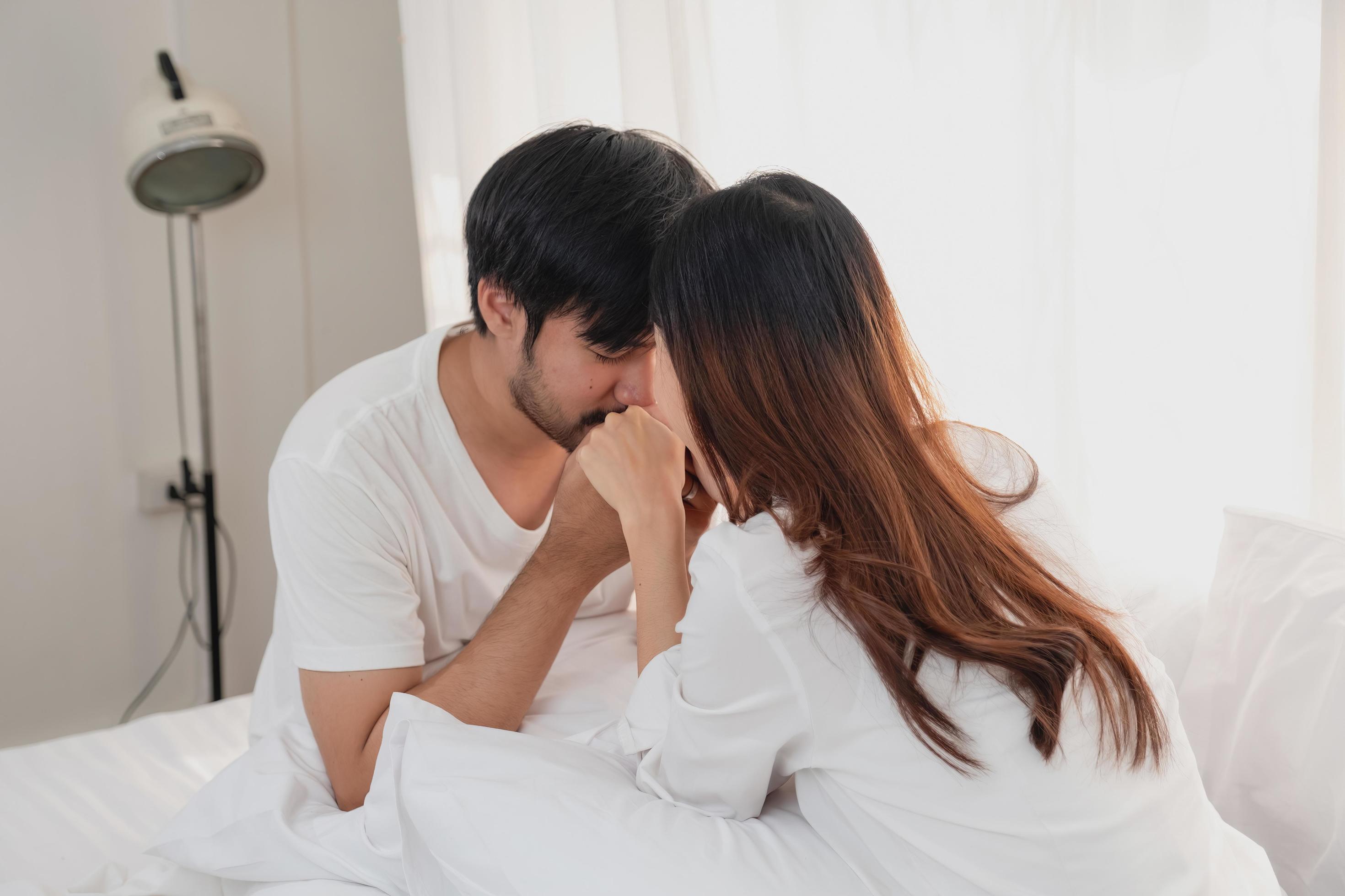 Happy young asian couple embracing, teasing, playing cheerfully in bed at home, romantic time to enhance family bonding. family concept. Stock Free