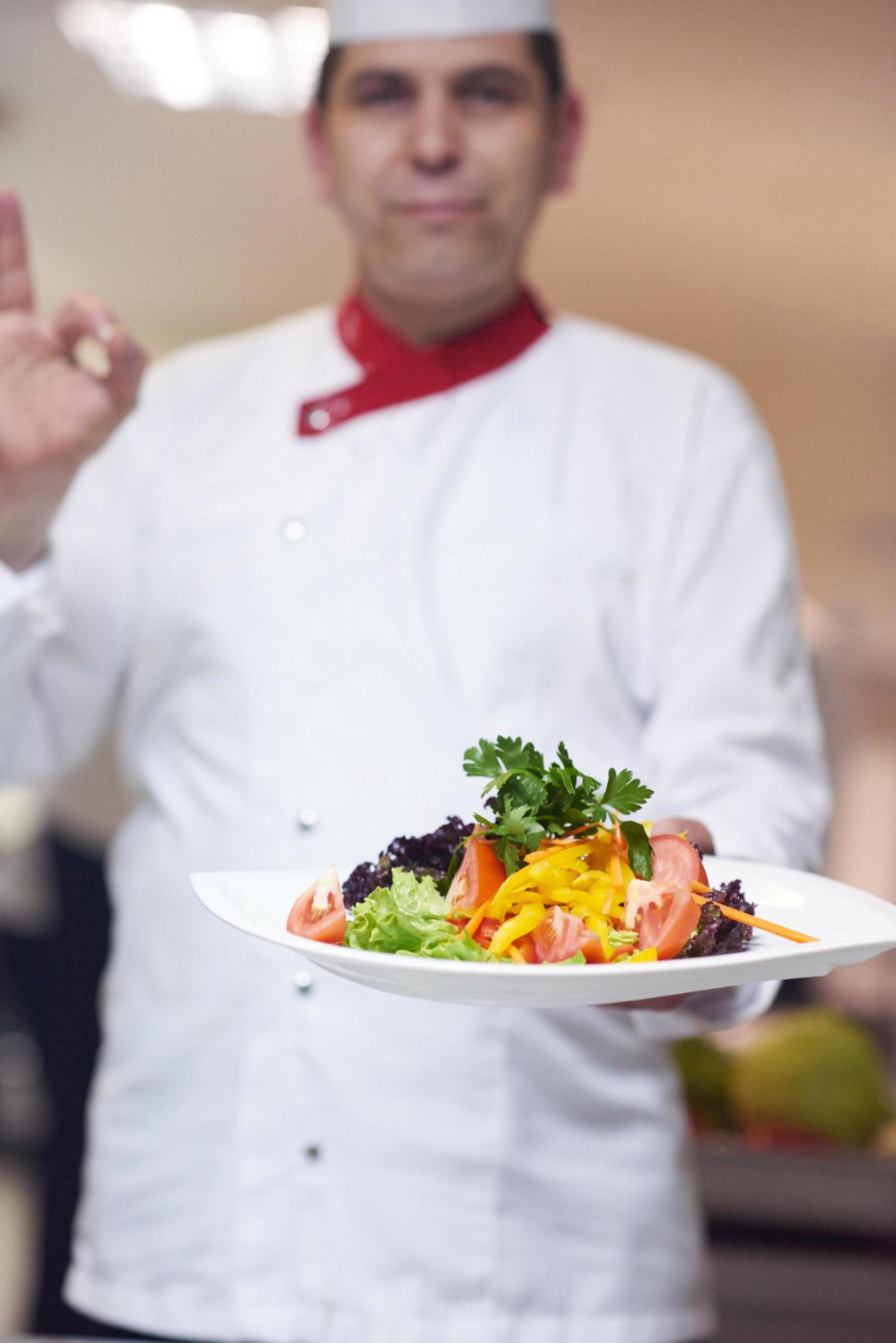 chef in hotel kitchen preparing and decorating food Stock Free