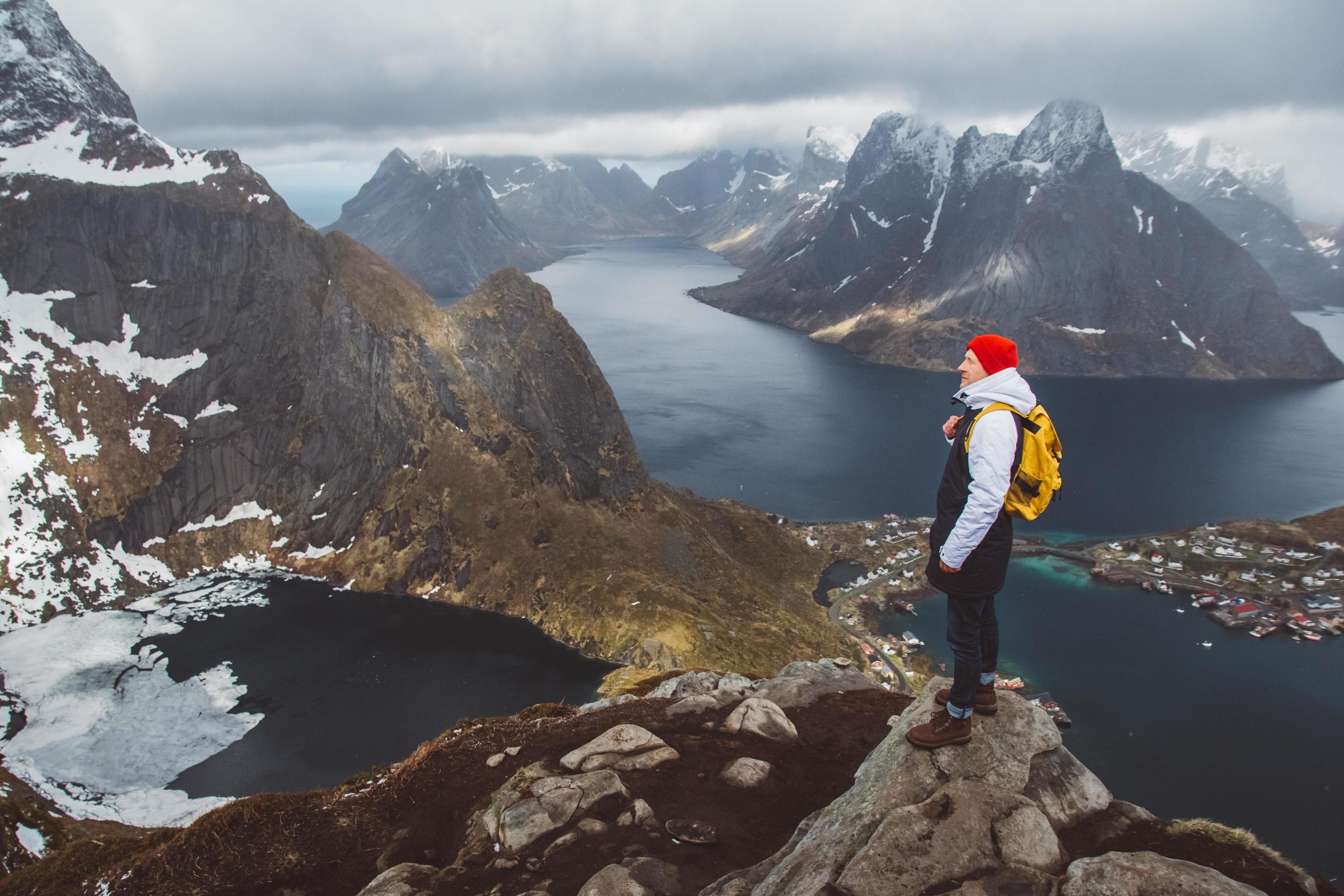 Man traveler hiking on Reinebringen mountain ridge in Norway lifestyle adventure traveling Stock Free