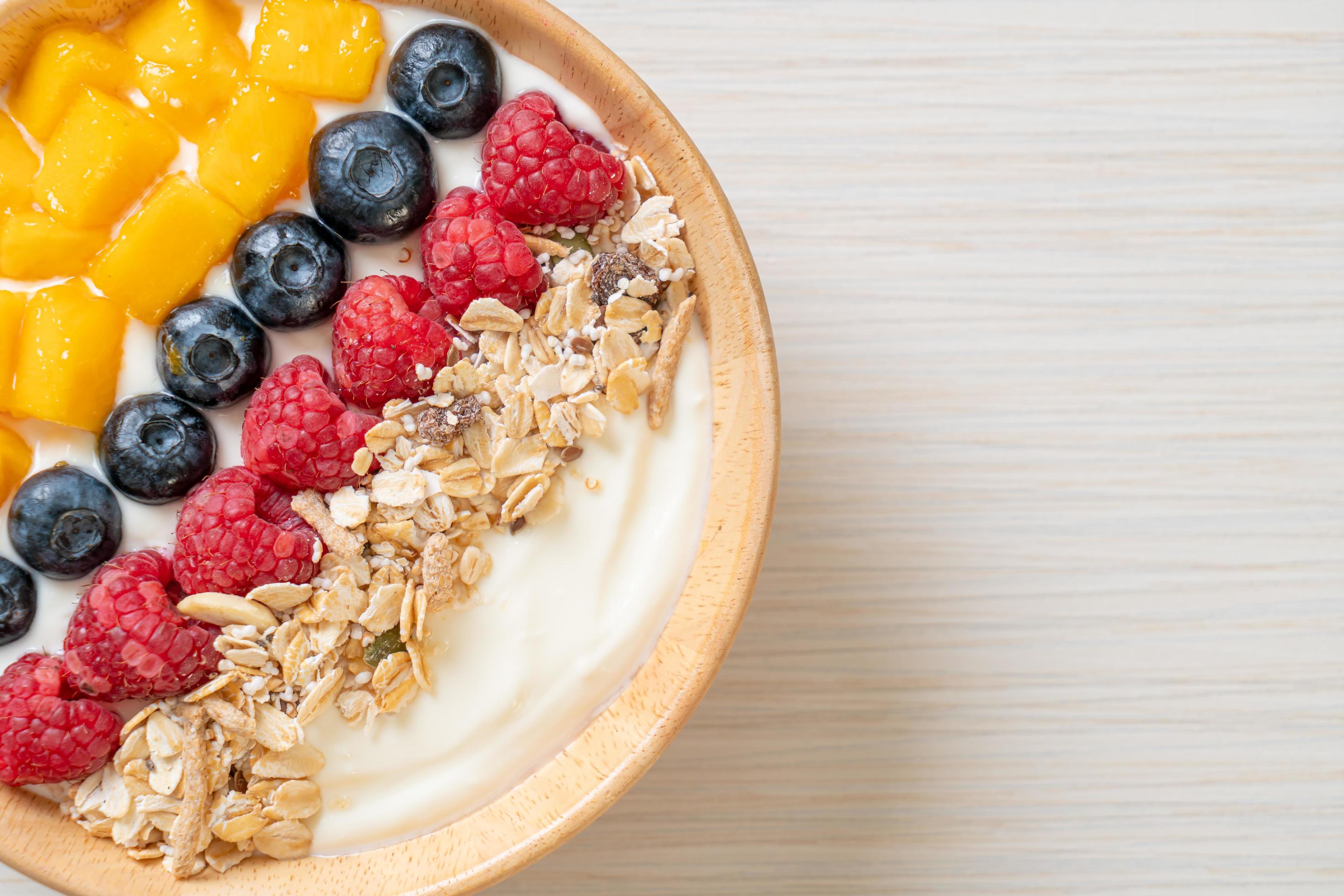 Homemade yogurt bowl with raspberry, blueberry, mango, and granola – healthy food style Stock Free