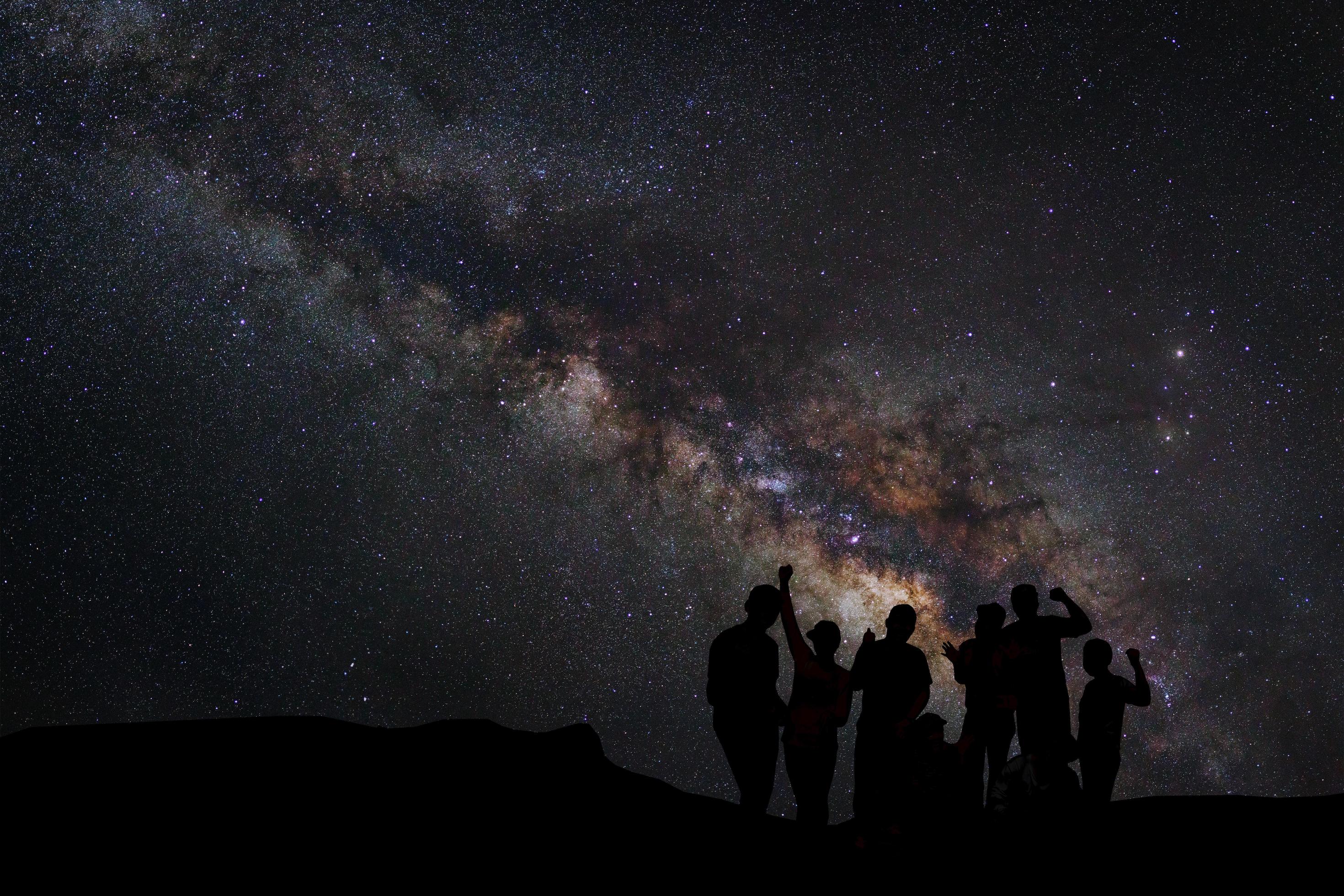 Landscape with milky way, Night sky with stars and silhouette of happy people standing on the mountain, Long exposure photograph, with grain Stock Free